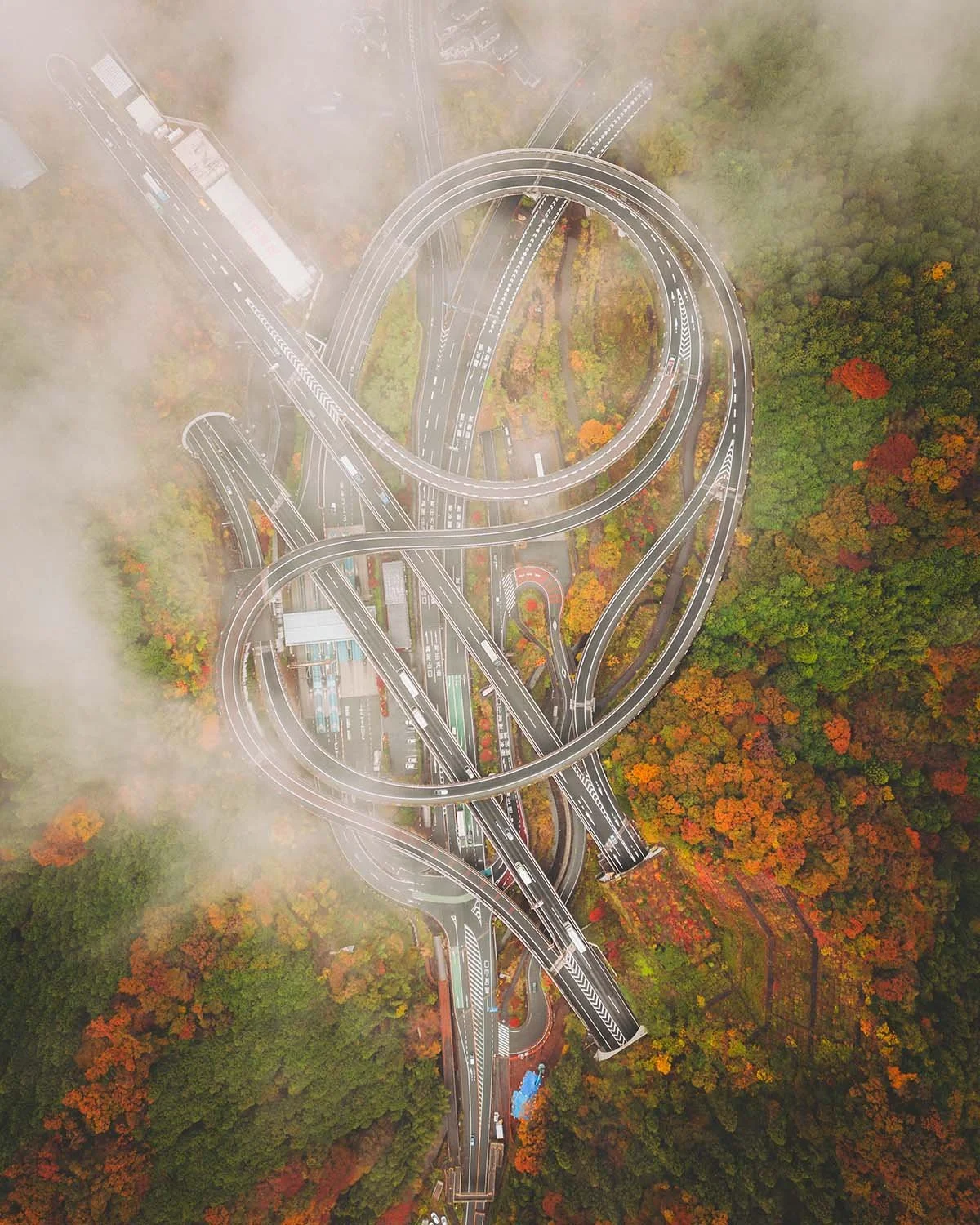 Vue aérienne drone échangeur autoroutier Takaosan Interchange Ken-O Expressway Hachioji Tokyo. Architecture infrastructure routière complexe courbes béton génie civil traffic routier forêt automne.