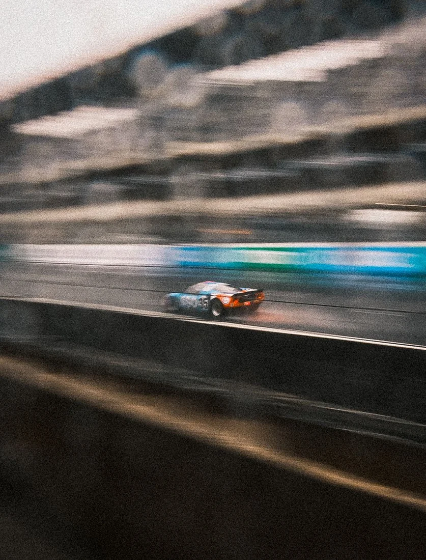 Voiture de course capturée à pleine vitesse sur circuit avec un effet de filé (panning) parfaitement maîtrisé. Photographie de sport mécanique dynamique.