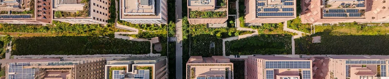 Architecture durable : vue aérienne zénithale d'un quartier moderne alliant béton, panneaux solaires et toitures végétalisées.