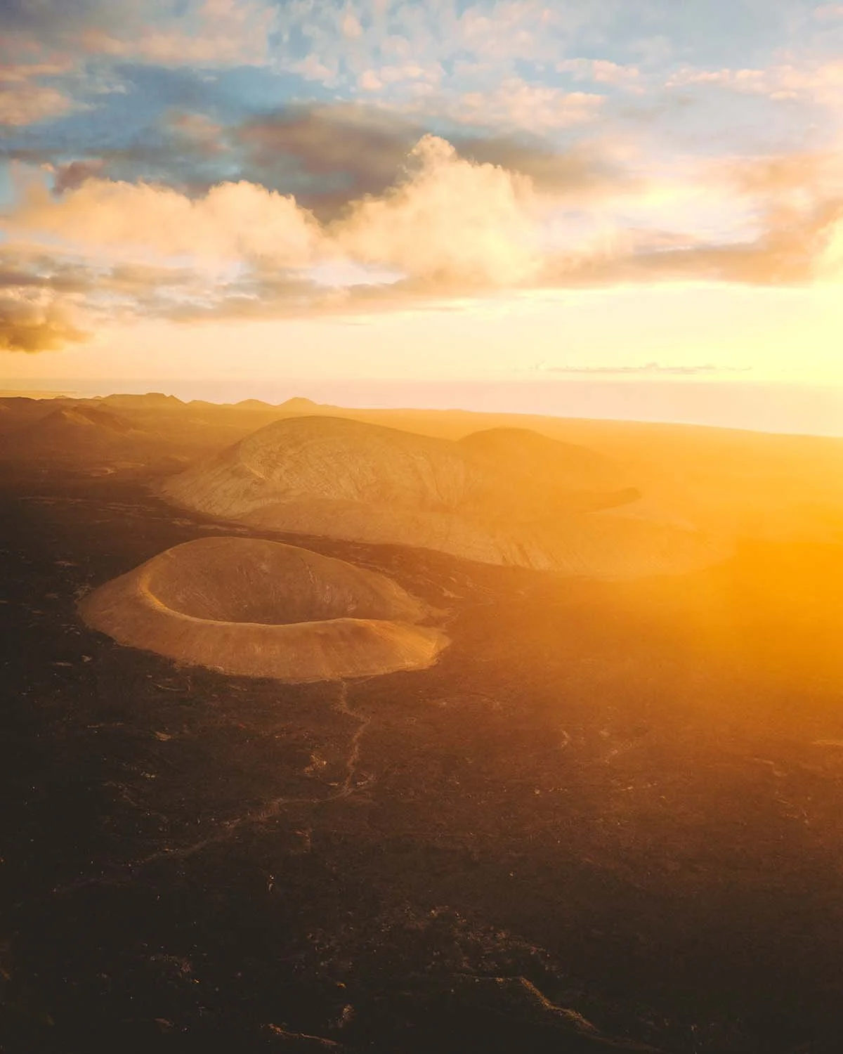 Les couleurs dorées du coucher de soleil illuminant le cratère du Volcán del Cuervo (Montaña del Cuervo) au cœur du paysage lunaire de Lanzarote.