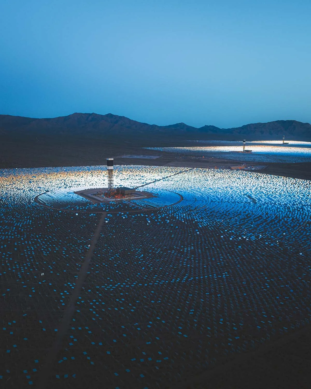 Vue aérienne drone centrale solaire thermique Ivanpah Solar Electric Generating System désert Mojave Californie Nevada. Champ miroirs héliostats énergie renouvelable technologie futuriste heure bleue.