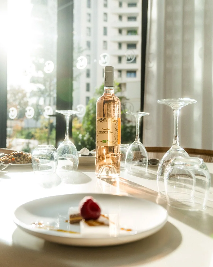 Ambiance "Art de vivre" en hôtellerie : mise en scène d'une bouteille de rosé et d'un dessert avec une belle lumière naturelle.