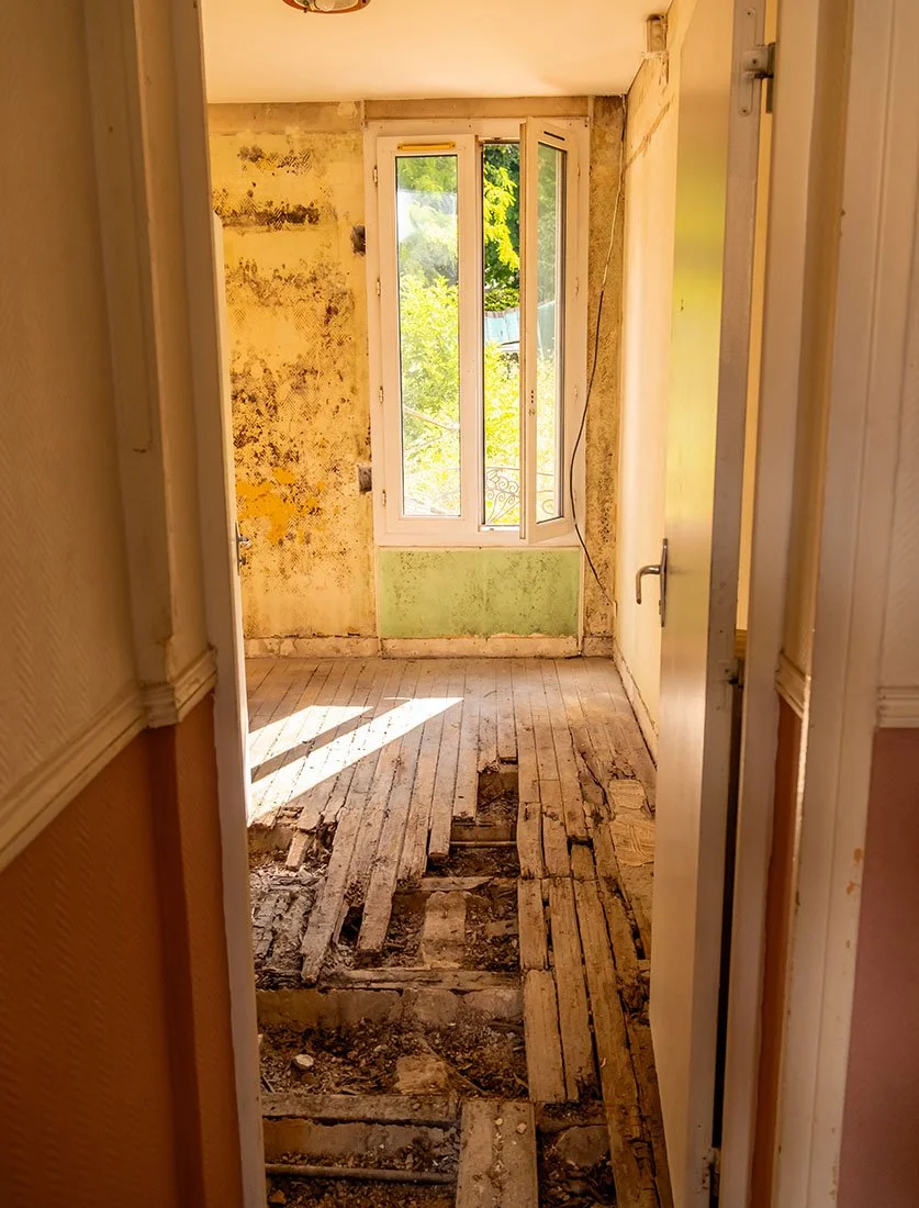 Vue d'un chantier de rénovation d'appartement montrant la dépose du parquet et la structure. Suivi de chantier BTP.