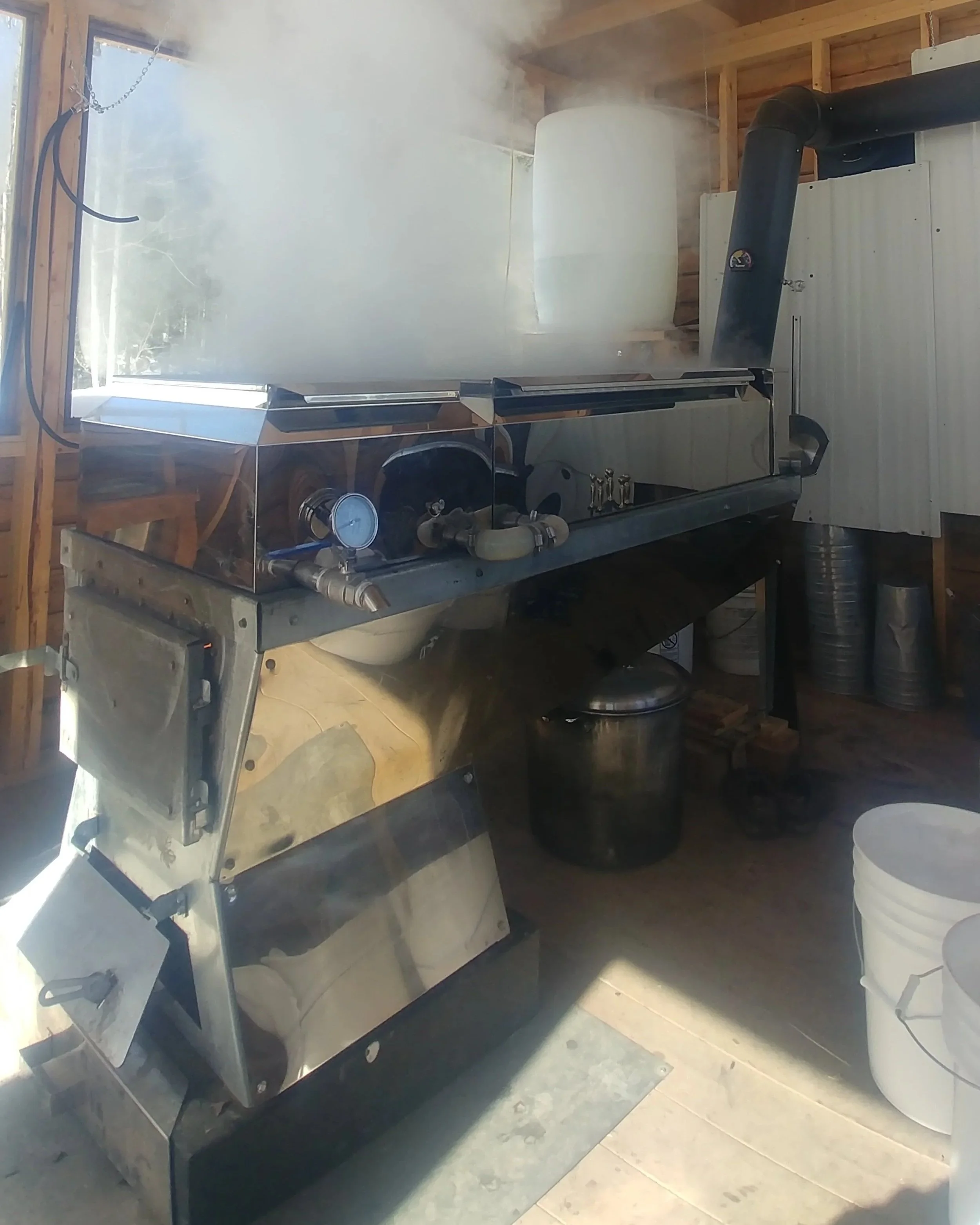 Une machine à vapeur dans un atelier ou un garage, avec de la vapeur qui s'en échappe, et divers équipements en arrière-plan.