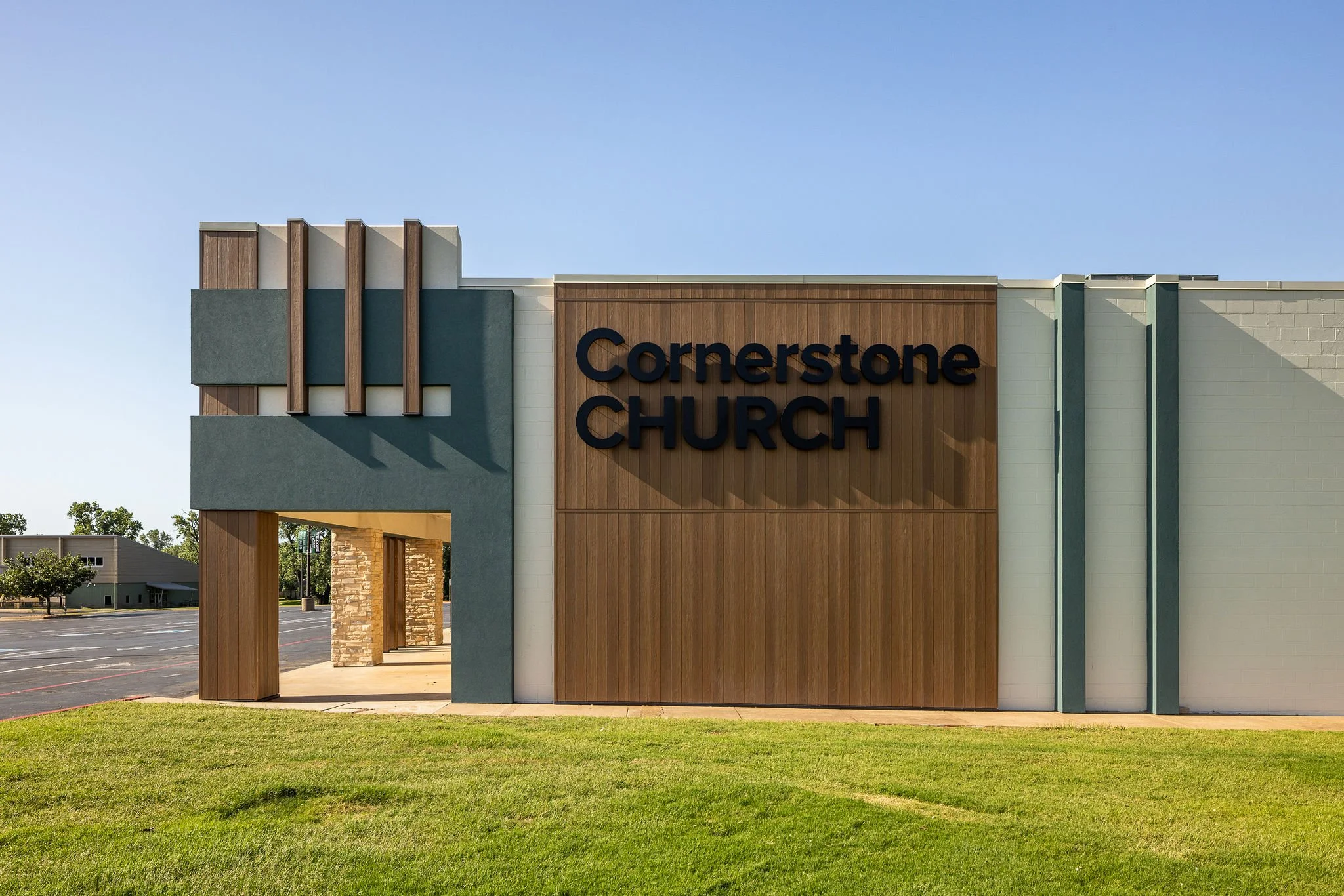Exterior of Cornerstone Church with modern design, wooden accents, green landscaping, and parking lot in the background.