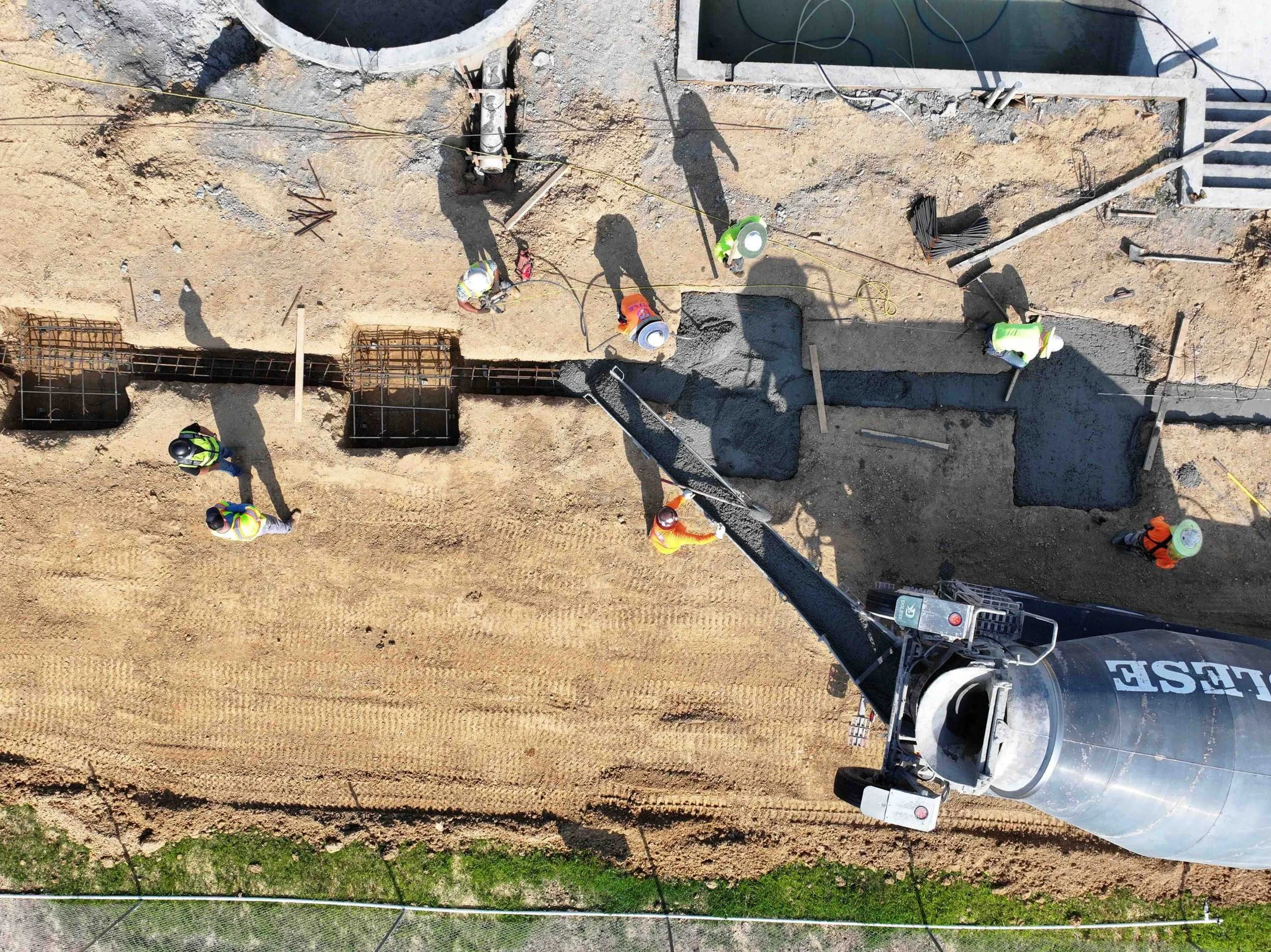 Construction workers pouring concrete at a construction site from a cement mixer truck.