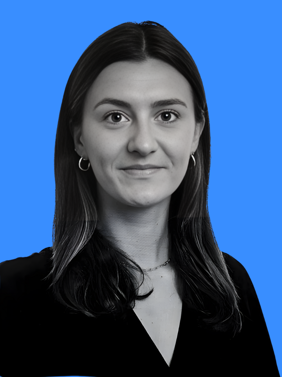 A black-and-white portrait of a young woman with long dark hair, wearing hoop earrings and a necklace, against a bright blue background.
