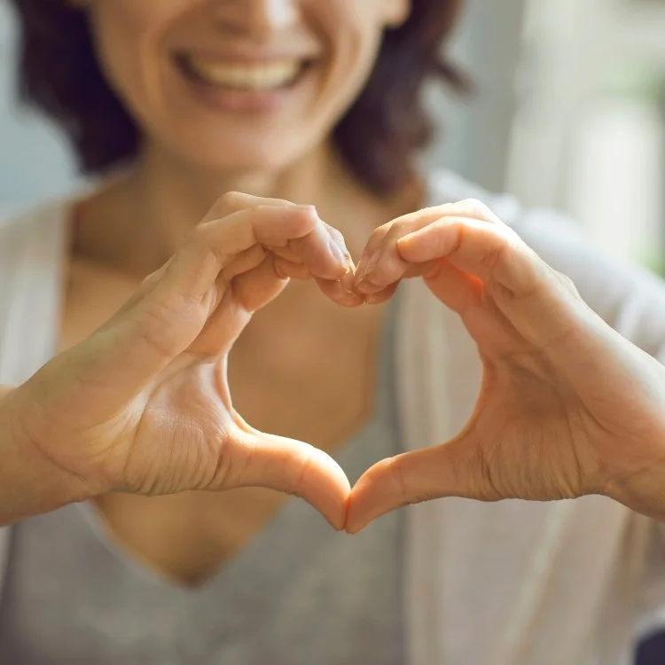 Smiling woman making a heart shape with her hands.