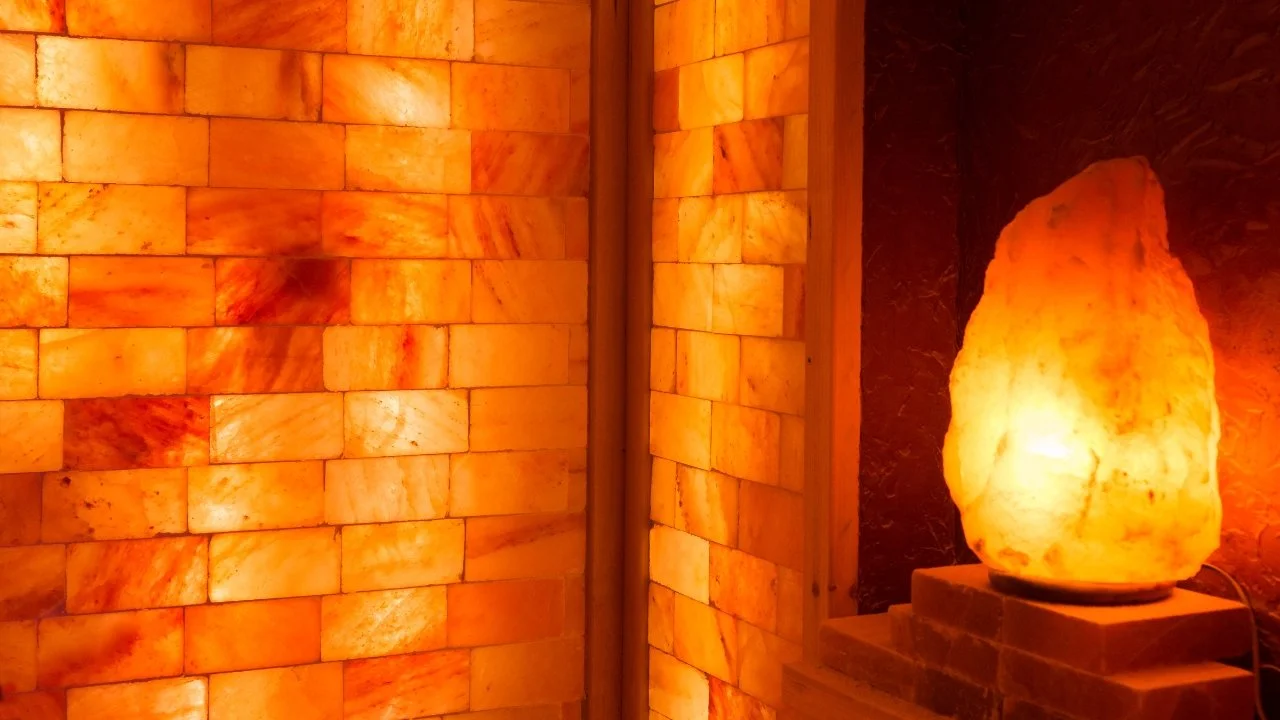 Interior view of a salt room with walls made of Himalayan salt bricks and a salt lamp on a brick platform.