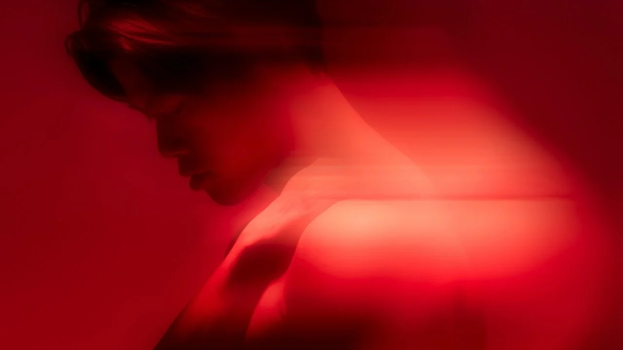 A woman with short hair looking down, with a red overlay and blurred motion effect.