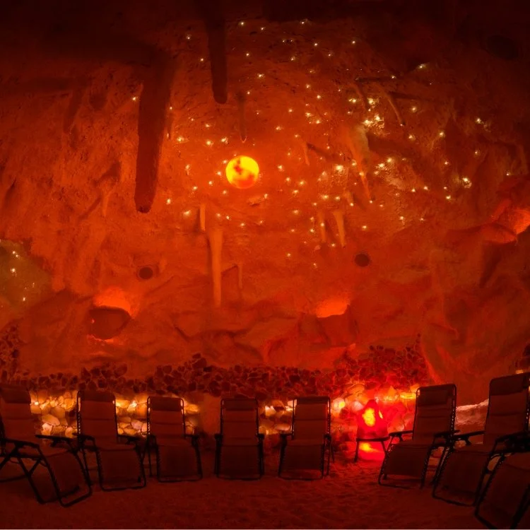 Indoor cave-like room with a mural of a nighttime sky and celestial objects on the ceiling, and chairs arranged facing the mural.