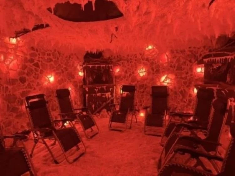 Indoor cave-like room with a mural of a nighttime sky and celestial objects on the ceiling, and chairs arranged facing the mural.