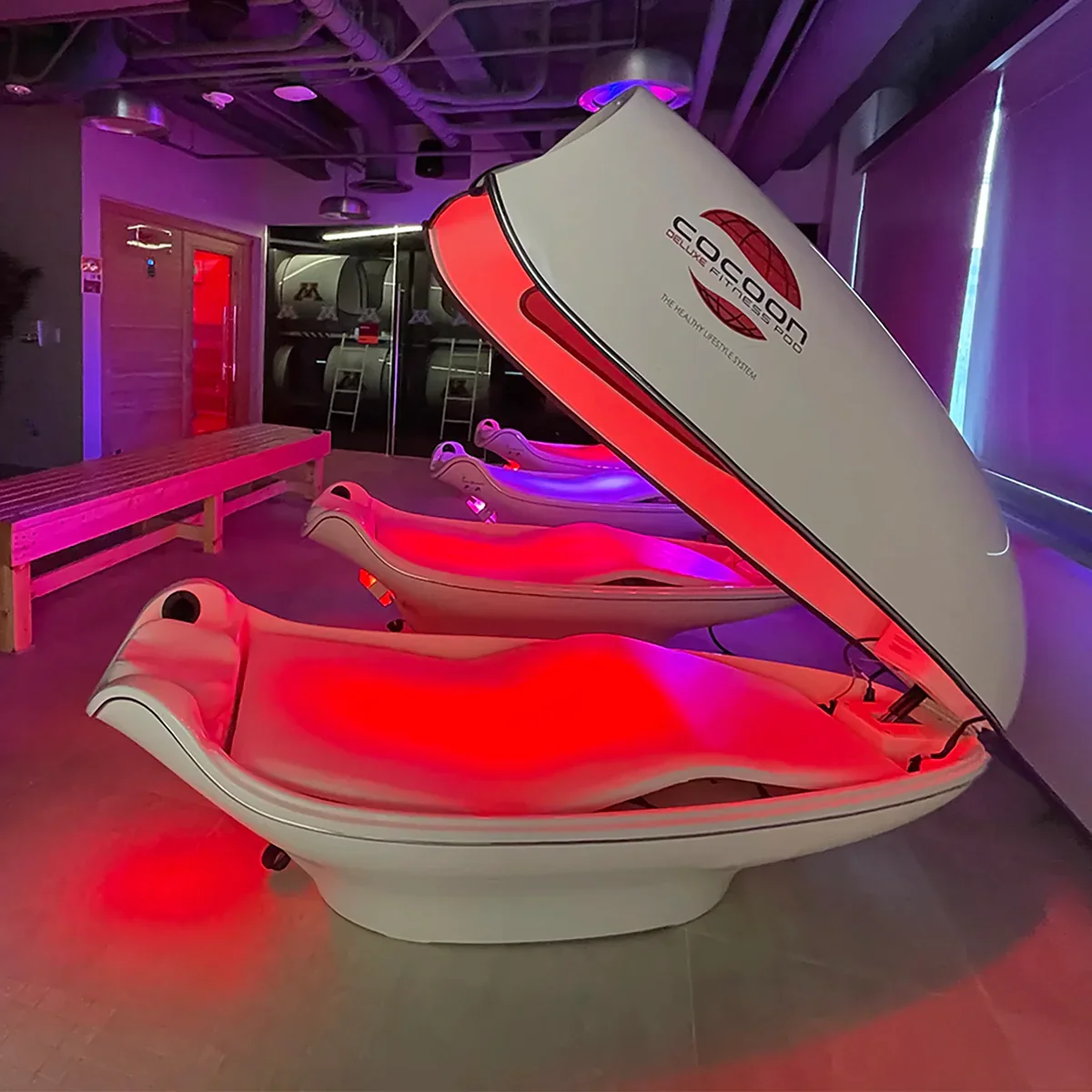 Close-up of two hands holding each other in front of a red light therapy device with circular LEDs.