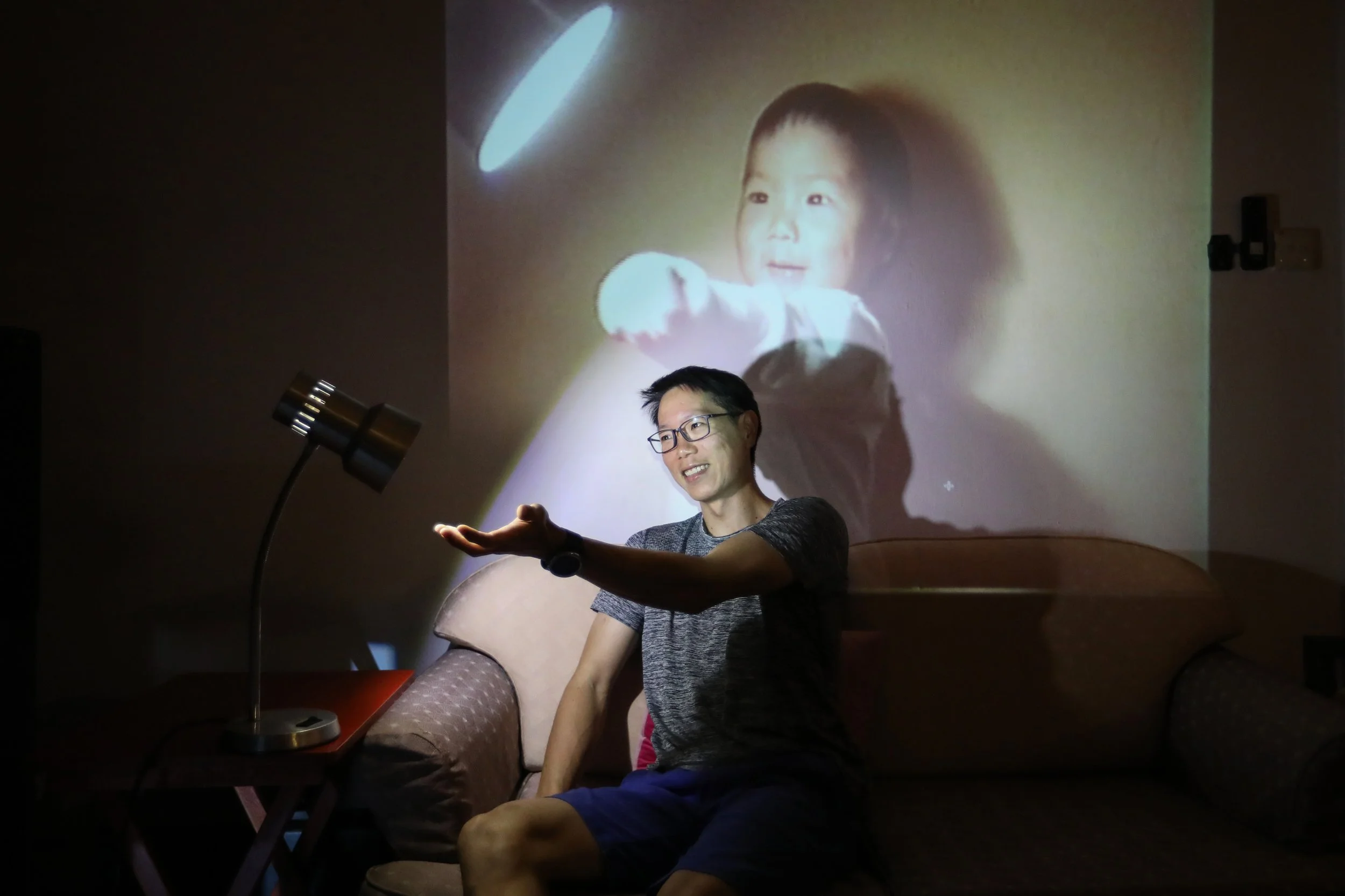 Mr Joel Seet extending his hand towards the same lamp seen in a 1989 home video recording his mother made when he was one year old.