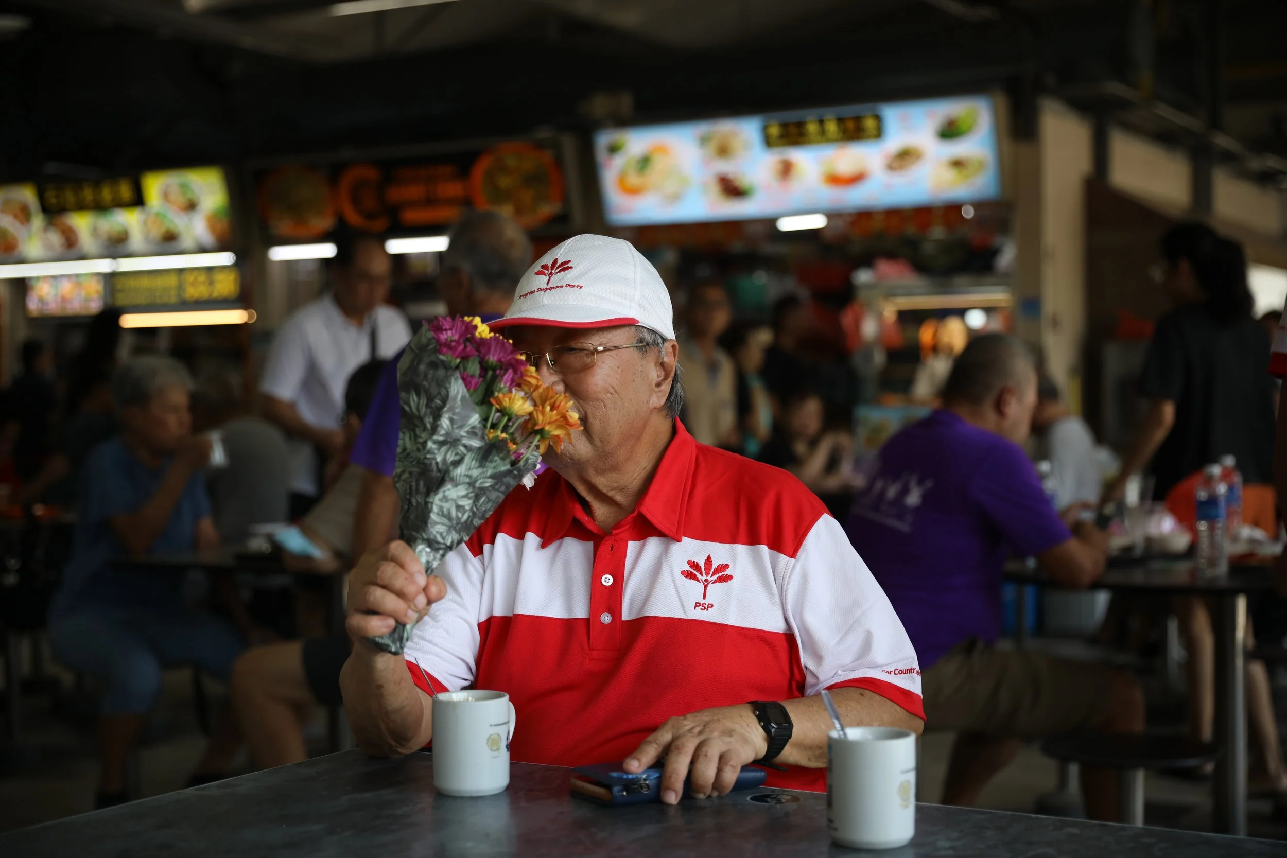 PSP chairman Tan Cheng Bock smells a bouquet of flowers gifted to him at the start of his walkabout at Mayflower Market & Food Centre. He had just celebrated his 85th birthday the previous day. (2025) 
