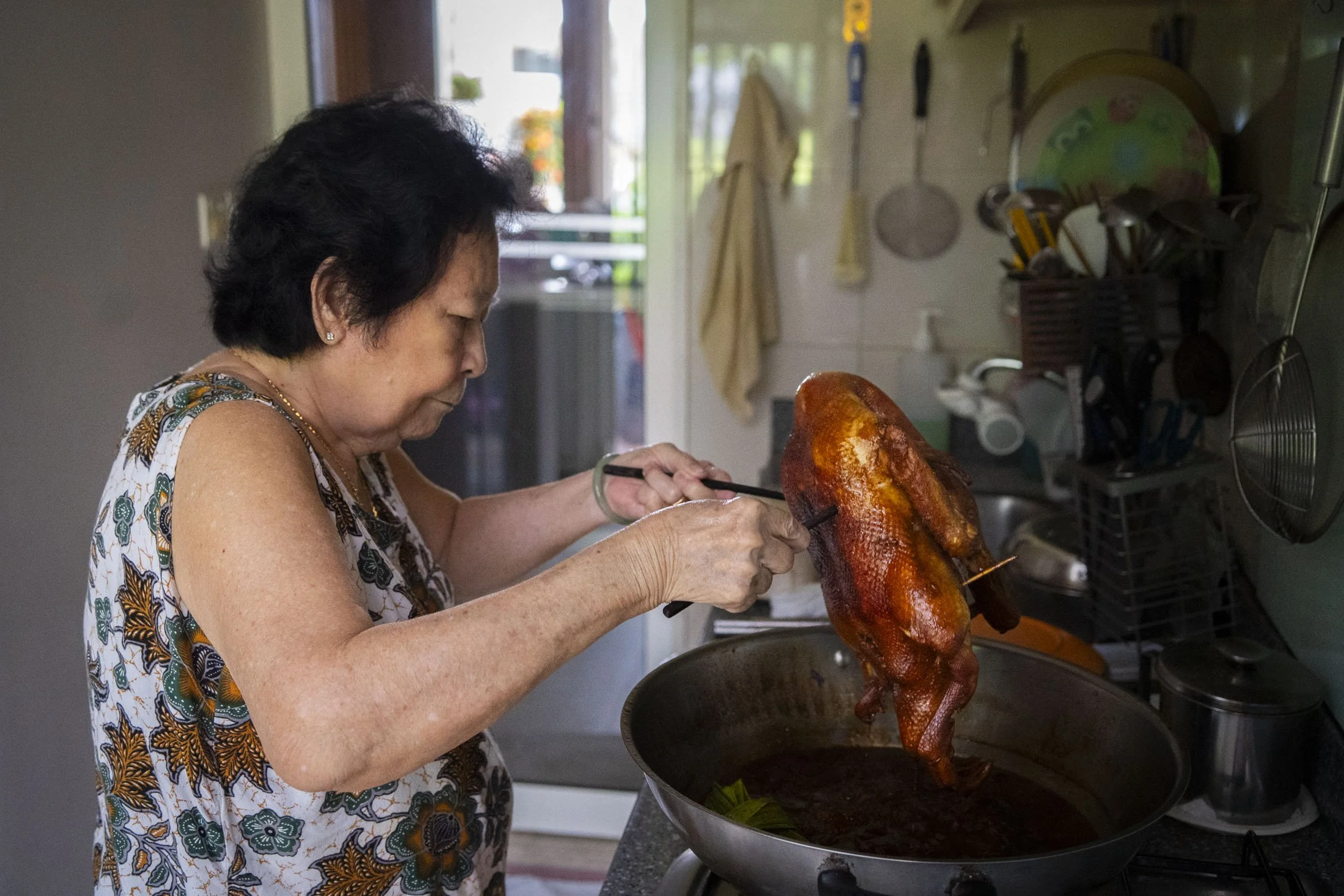 Mdm Lim fishes the braised duck out of the wok.