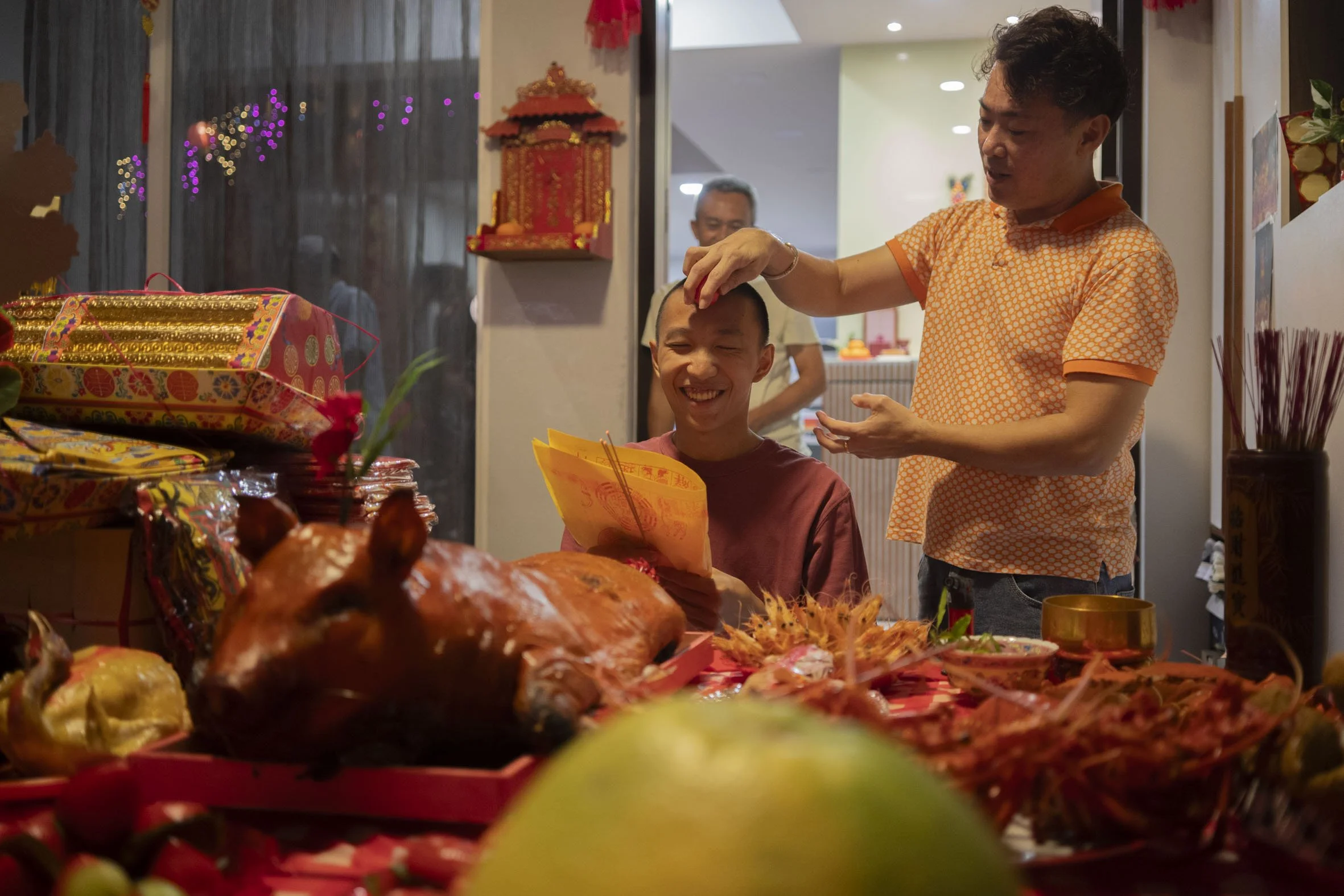 At 12AM, the “luck-renewing” ceremony began.   Mr Ng Zheng Ning Don (left), 18, currently in National Service, kneeled before the altar holding his birth chart and three joss-sticks.  After circling Mr Ng’s head with a red egg thrice while muttering 