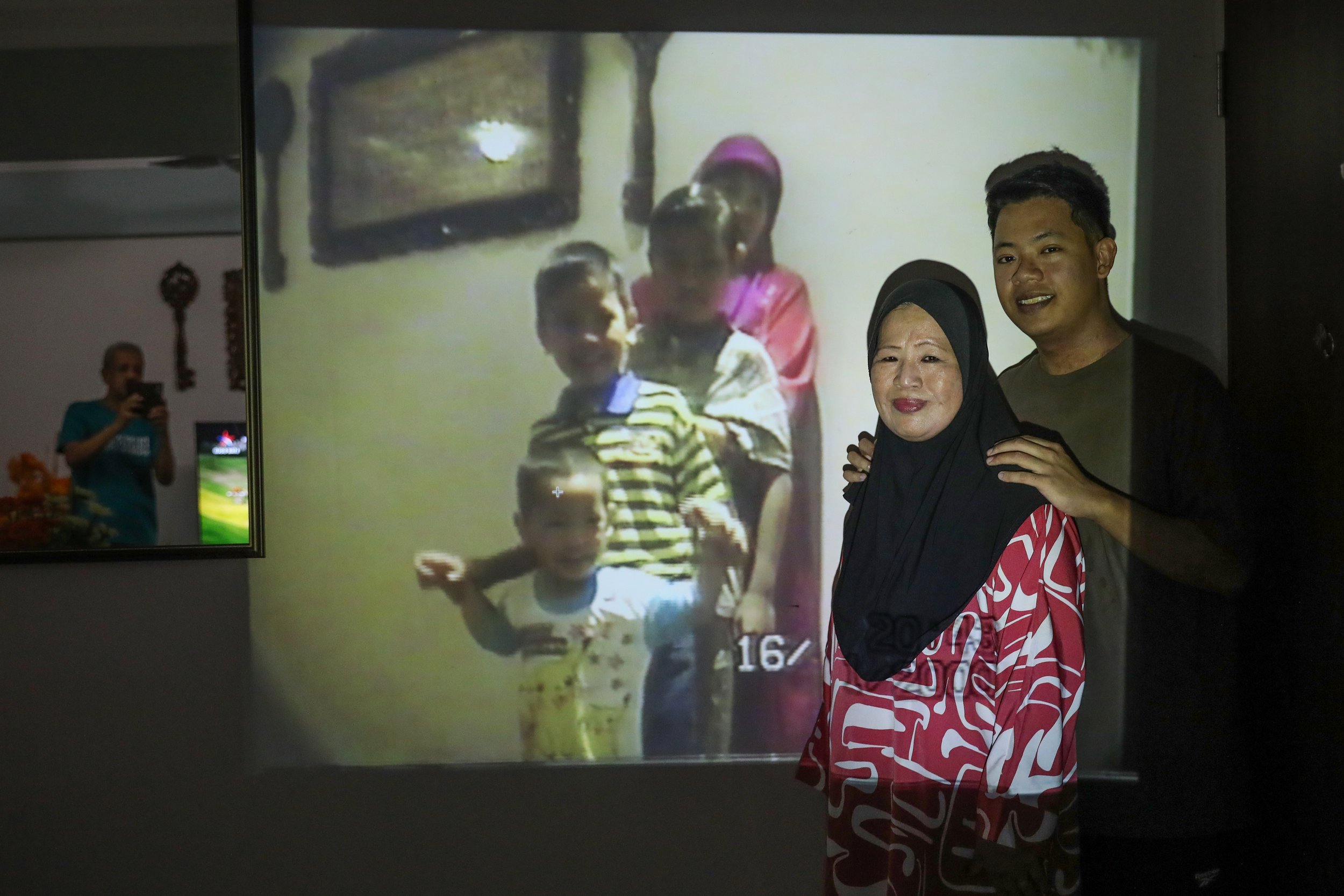 Mr Muhammad Zaki Saifee and his mother, Madam Haslinah Abdullah, 67, a homemaker, recreating a moment from a 2000 home video recording - albeit without his two older brothers. Meanwhile, his father Mr Saifee Saharan, 71, seen in the mirror’s reflecti