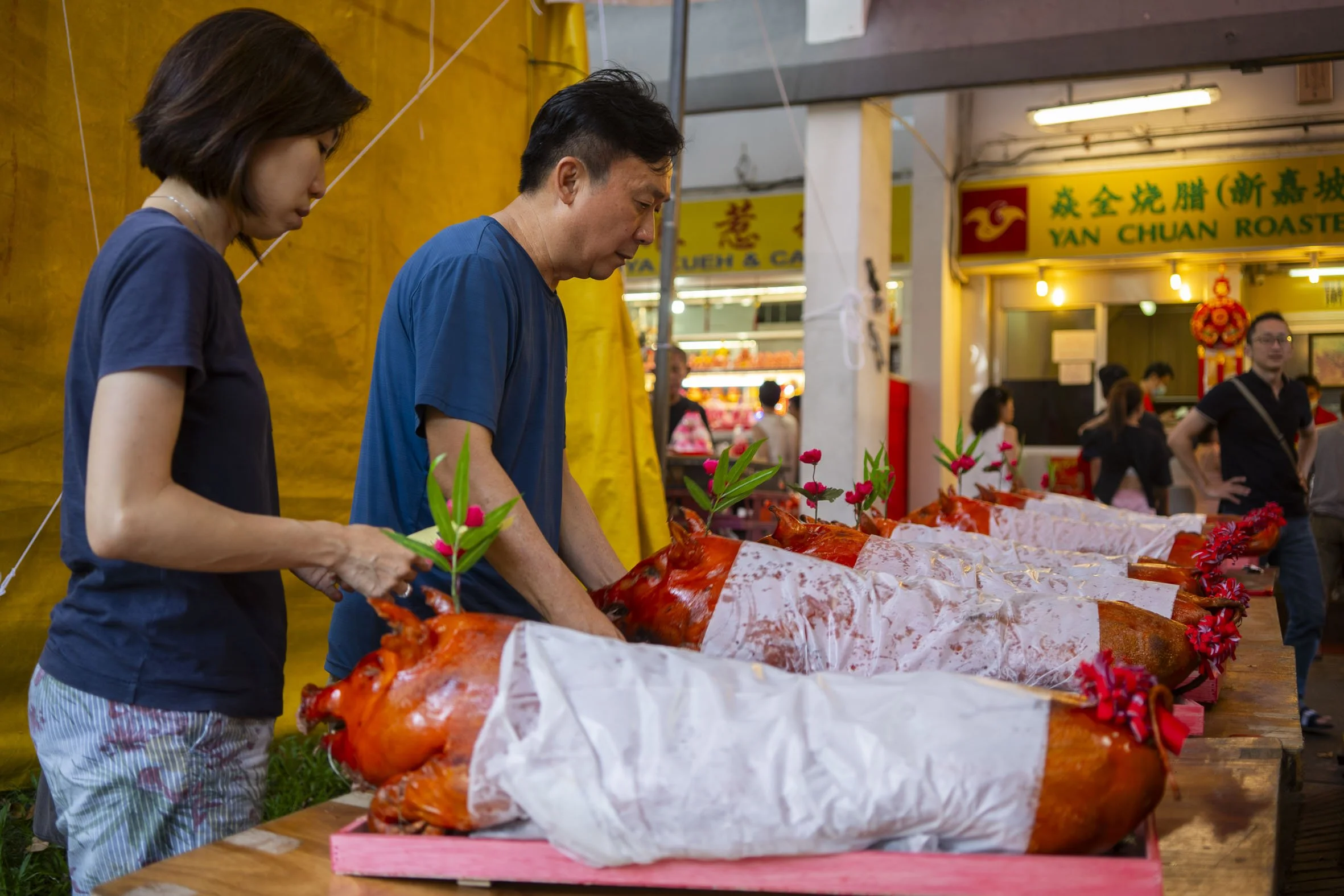 While Mdm Lim busied herself with preparations at home, her son, Mr Ng Soon Keong, 57, and Mdm Lee head to collect their whole roast pig pre-ordered from a month ago.   

Outside the shop, rows of roast pig line the table. After checking their order,