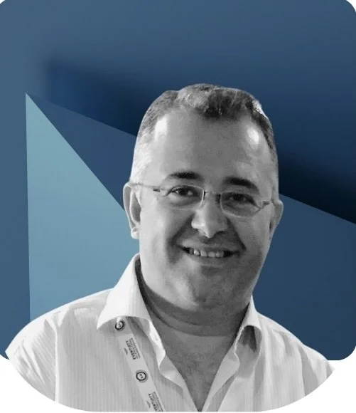 A smiling man wearing glasses and a collared shirt, posed against a stylized blue background.