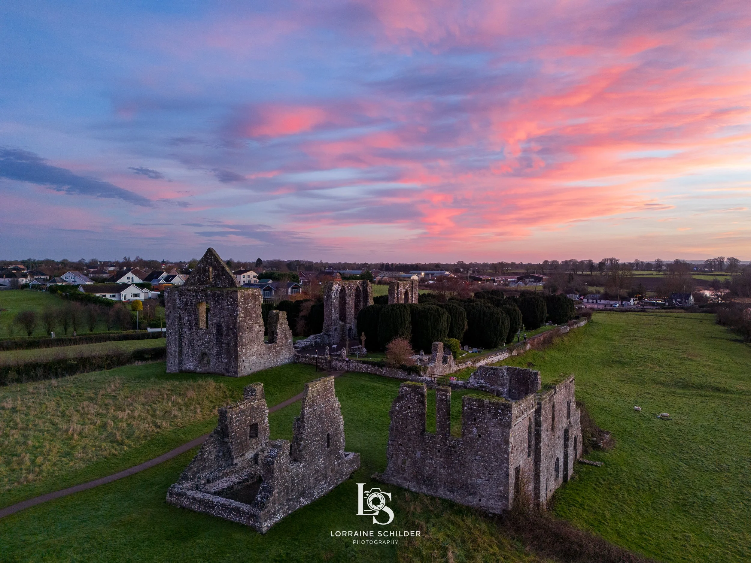 Overhead view of ancient Newtown ruins in a grassy area under a colorful sky at sunrise. Trim, Meath.