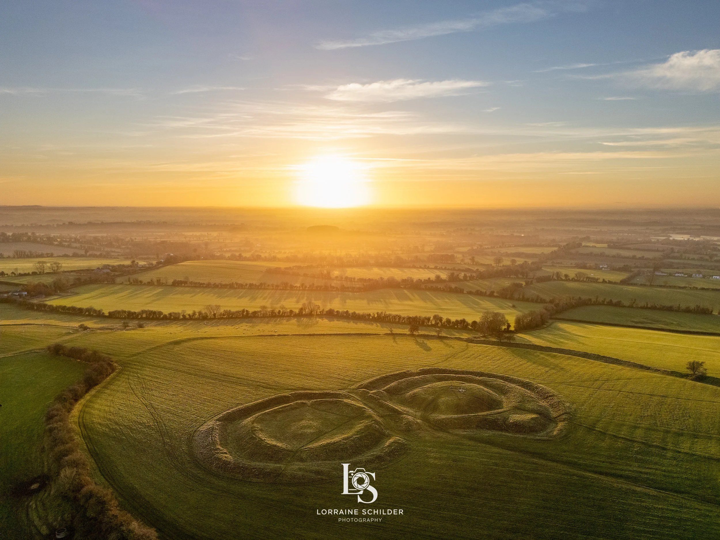 Aerial view of farmland at sunset with two crop circles in a green field.