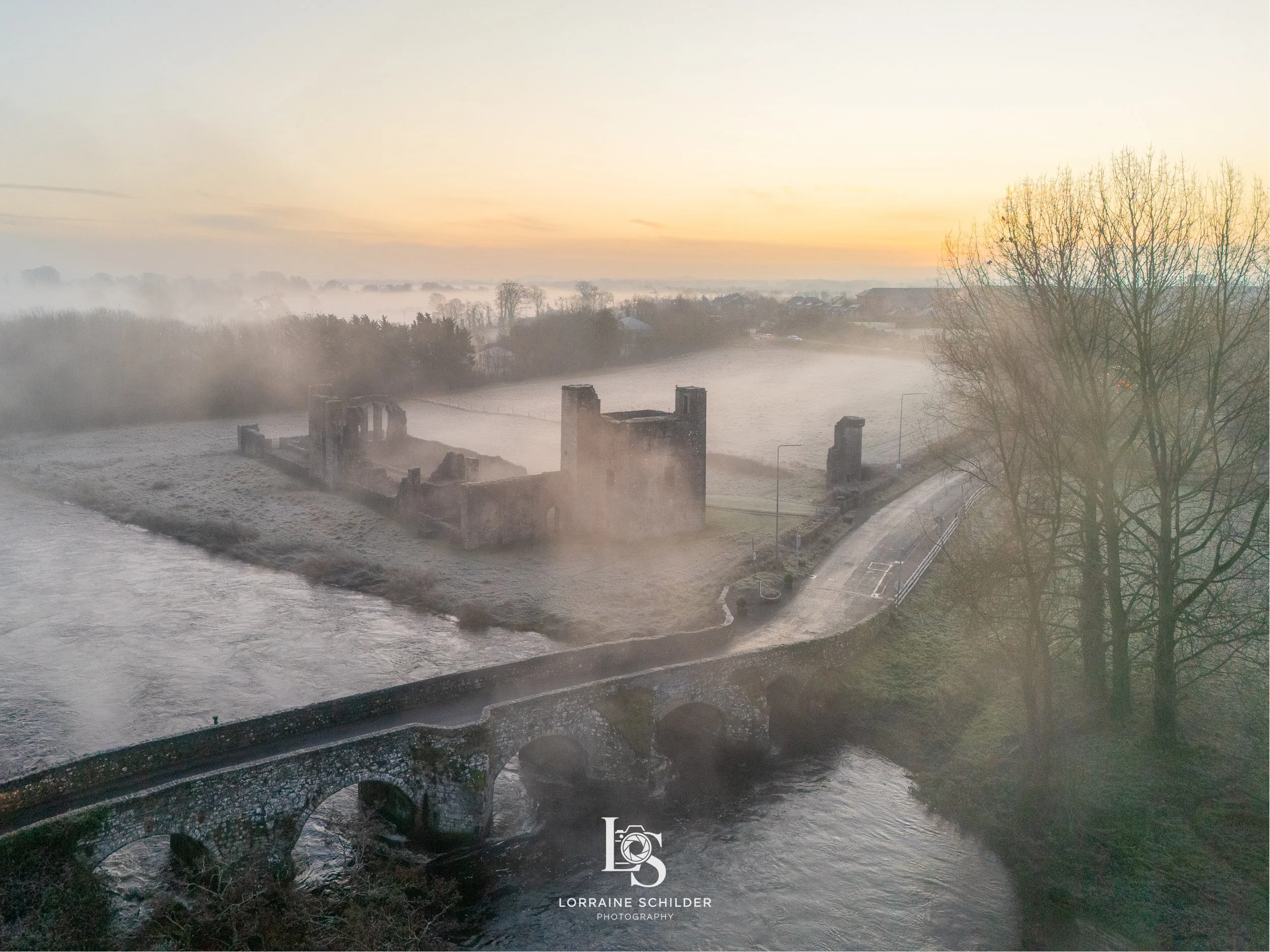 Aerial view of Newtown ruins next to the River Boyne with a misty landscape at sunrise and leafless trees around.