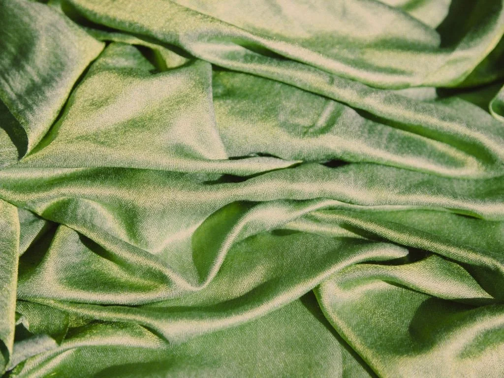 Close-up of green fabric with folds and textures.