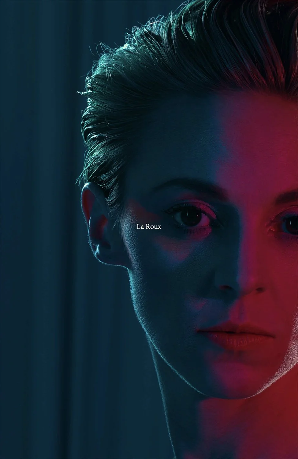 Close-up of La Roux's face with styled hair, illuminated by blue and red lighting, with the text "La Roux" on her cheek.