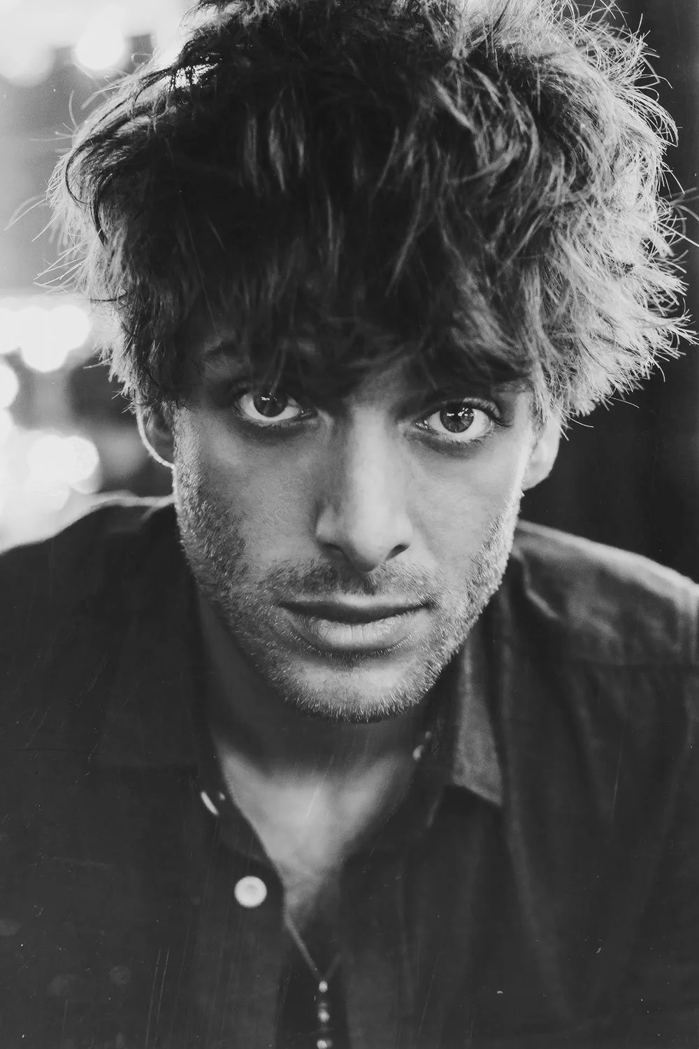 Black and white portrait of Paolo Nutini with tousled hair, staring directly at the camera with a serious expression.