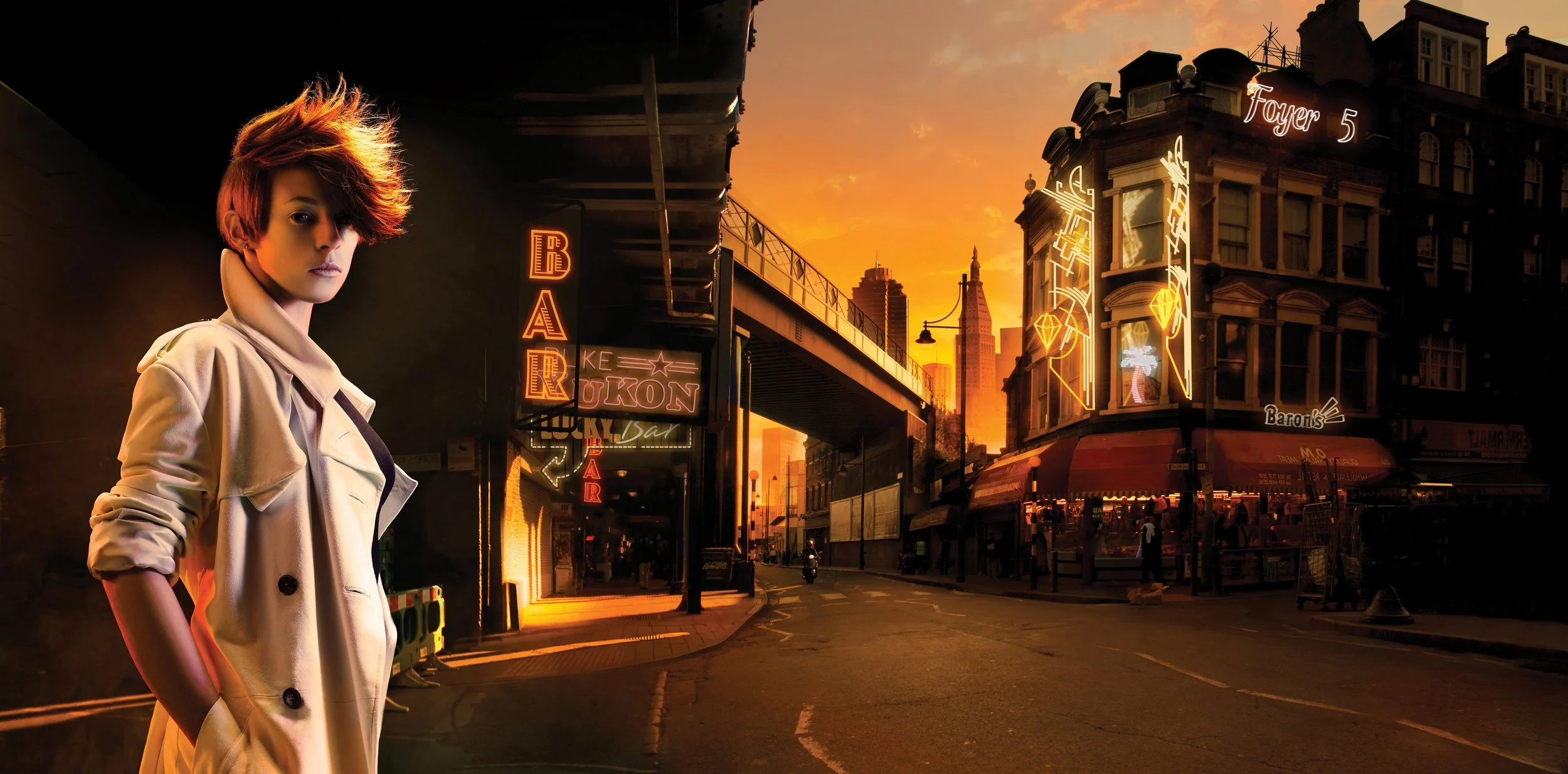 La Roux with short, layered red hair in a tan trench coat standing on a city street at sunset, with neon signs and tall buildings visible in the background.