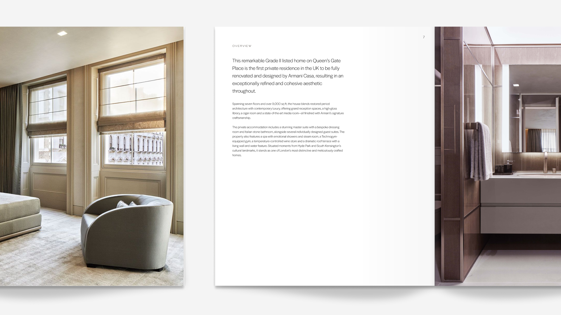 Photo of a hotel room interior with large window, beige walls, and modern furniture, including a gray armchair and a beige bed. A separate bathroom vanity with a mirror and towel is visible on the right.