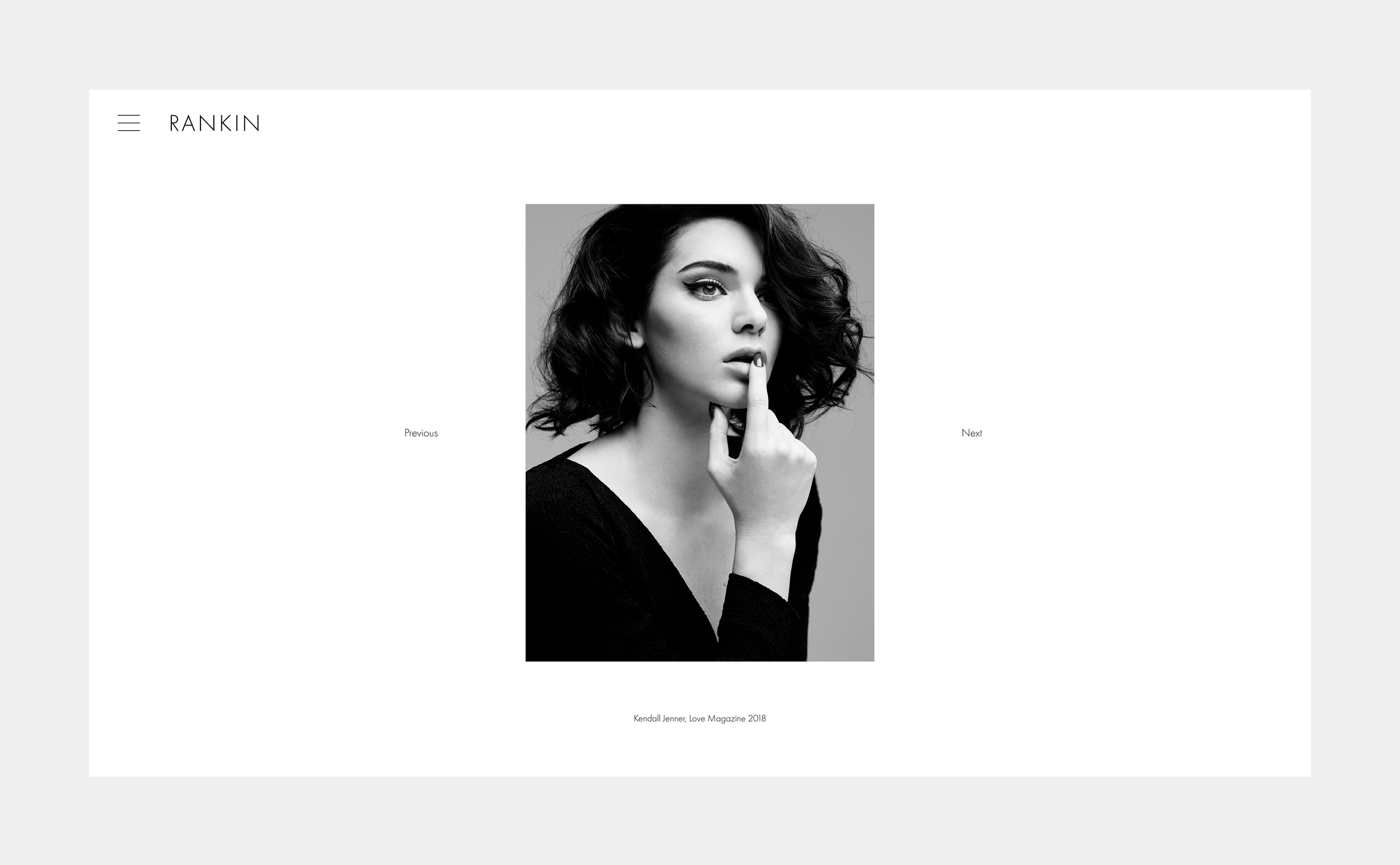 Black and white portrait of a woman with curly hair, looking at the camera with her finger near her lips. The image is on a webpage with navigation options and the text "Kendall Jenner, Love Magazine 2018" at the bottom.
