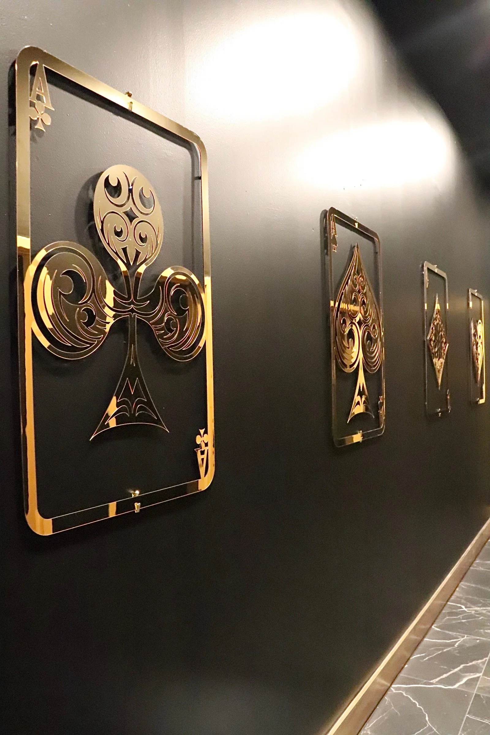 Wall with decorative gold and black playing card themed wall art featuring spade symbols.