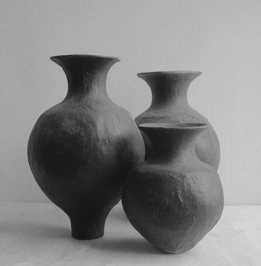 Three ceramic vases with a textured surface, arranged on a flat surface against a plain background.