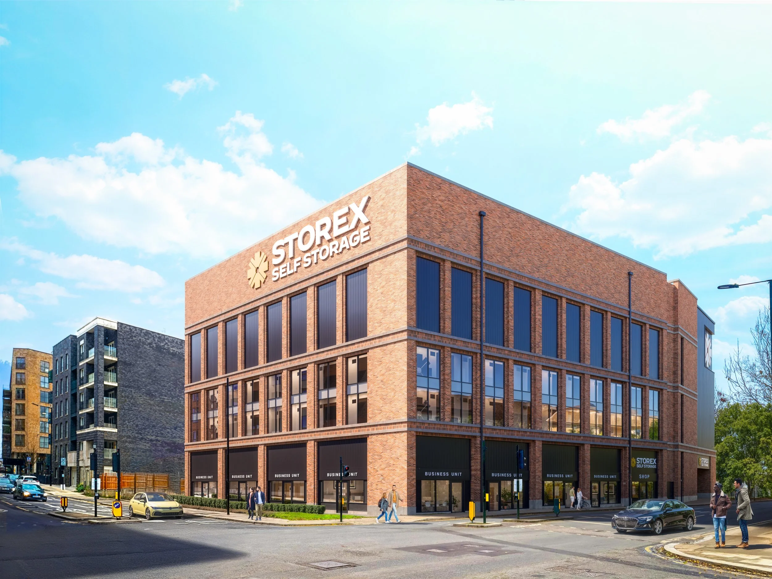 A large brick building with a sign reading 'STOREX Self Storage' on top, located on a city street with pedestrians and cars, under a partly cloudy sky.