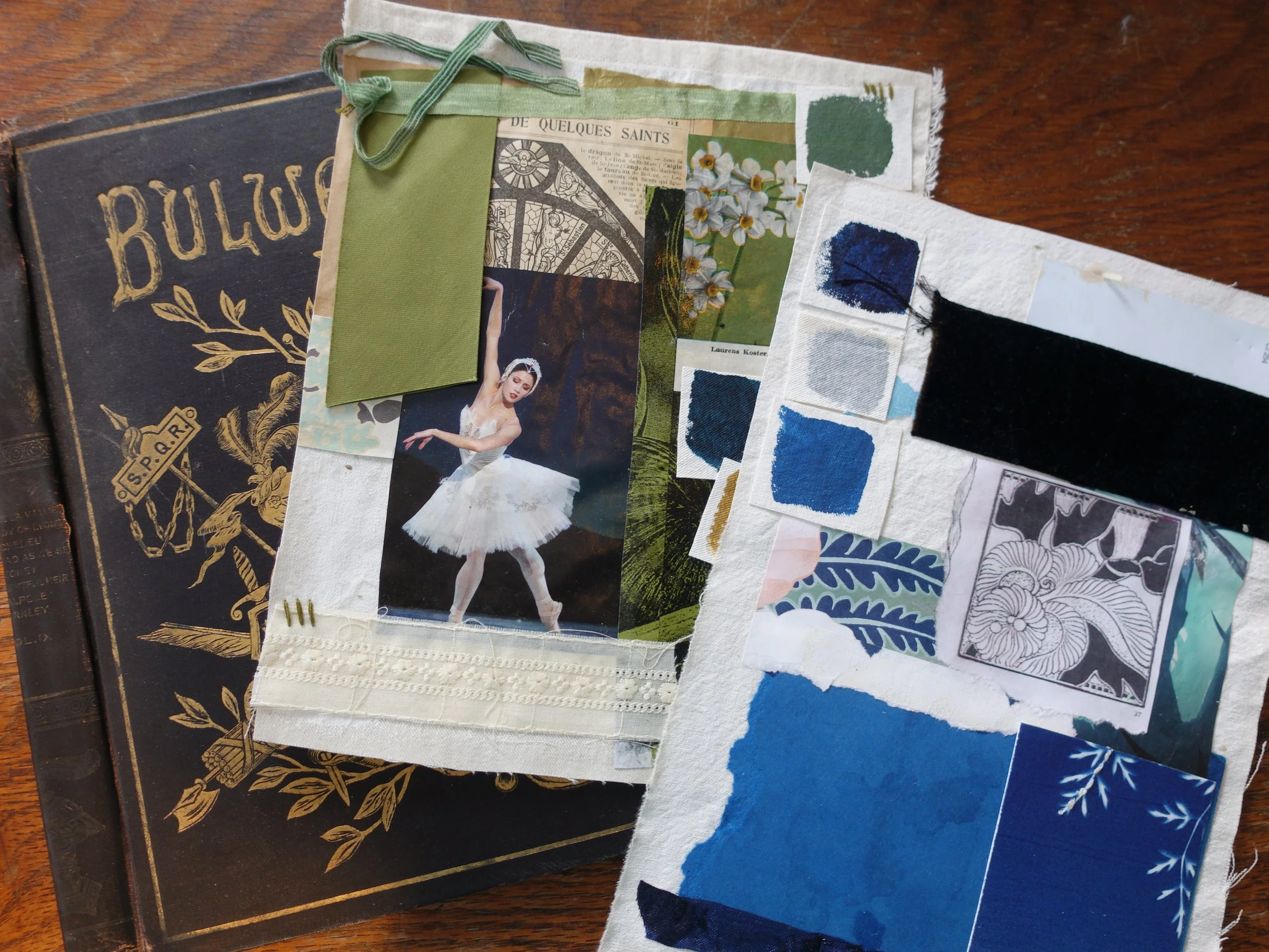 A collage of fabric samples, paint swatches, and cutouts on top of a black book with gold decorative text and leaves. The fabric includes a photo of a ballet dancer, a black velvet strip, and various colorful patterns and textures.