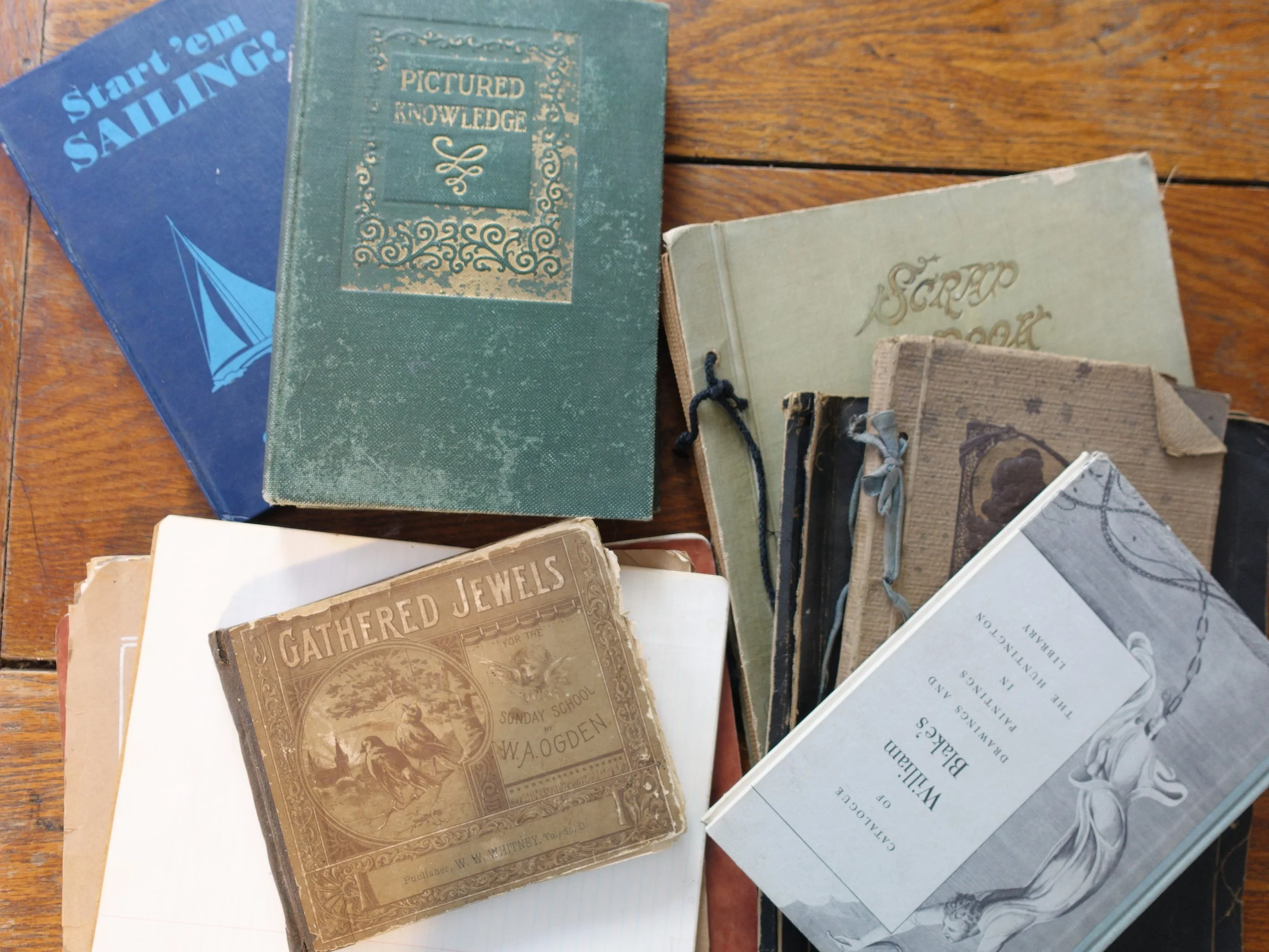 A collection of vintage books on a wooden surface, including titles about knowledge, jewels, and poetry.