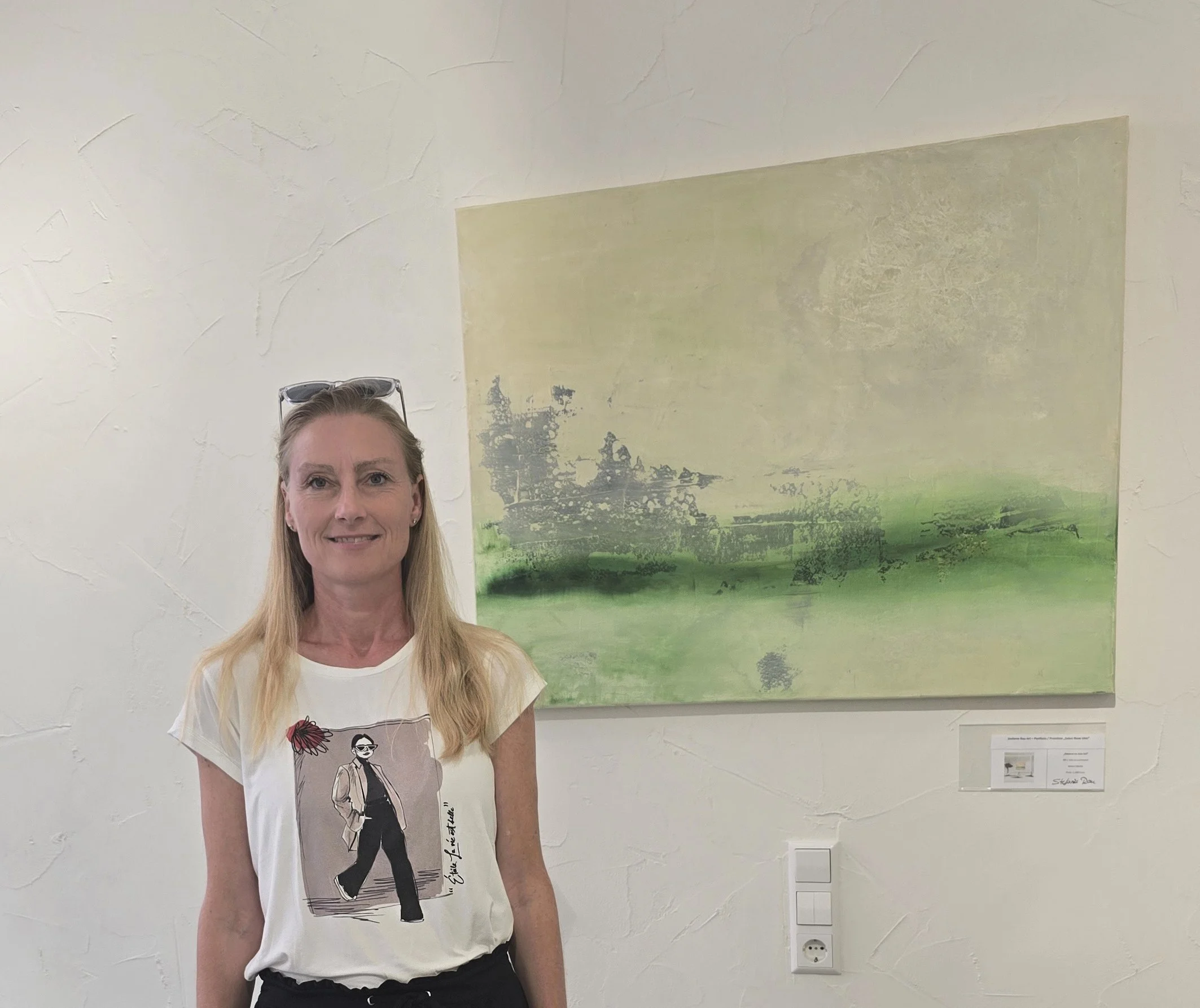 Die Künstlerin Stefanie Rau steht vor einem abstrakten Gemälde im Salon ARose in Ulm  aus der Serie Balance.