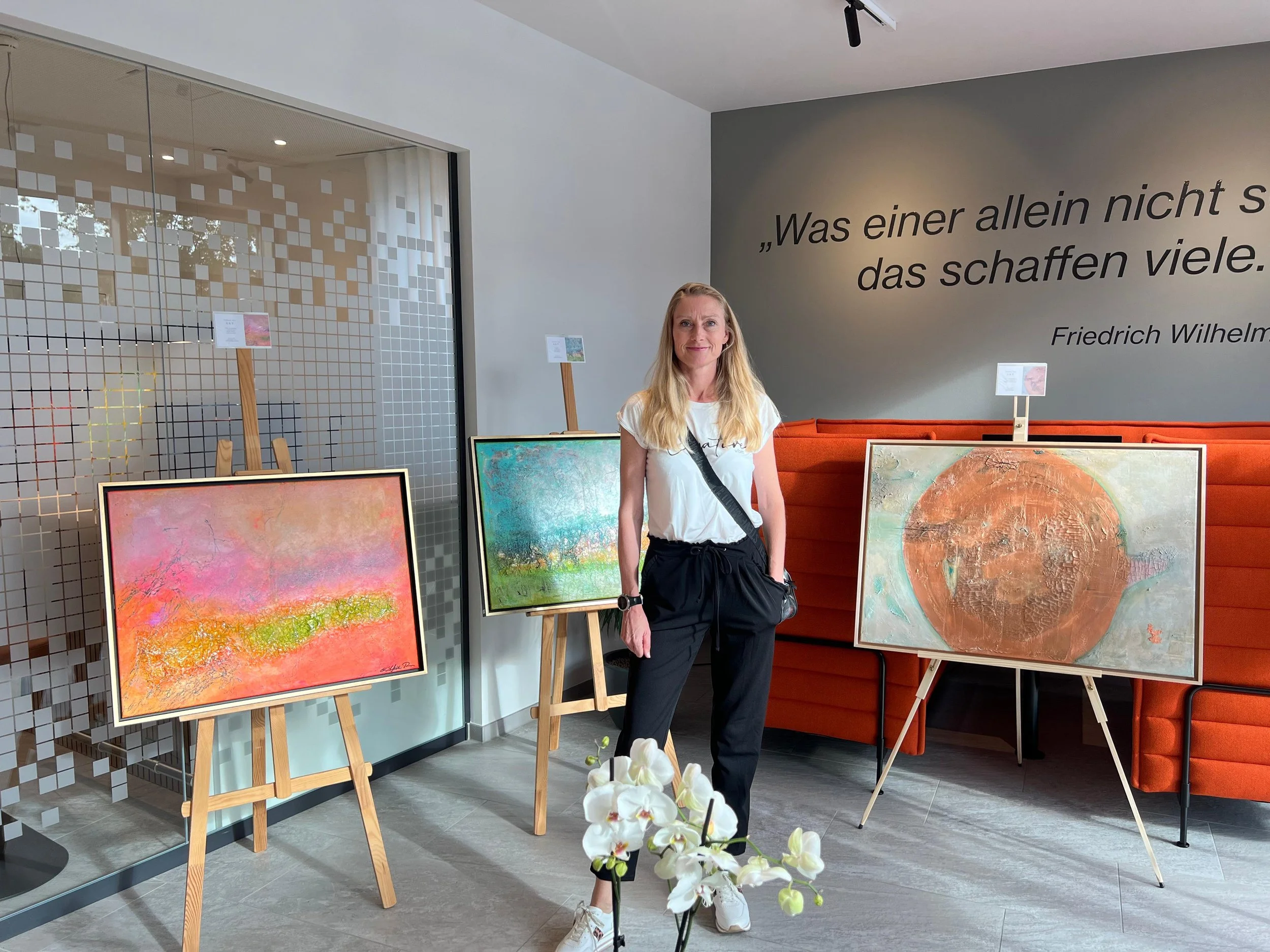 Künstlerin Stefanie Rau vor ihren abstrakten Werken bei der Ausstellung im Juli 2025 in der VR-Bank Donau-Mindel eG 
