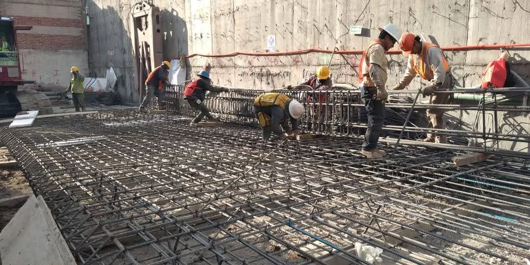 Construction workers installing steel reinforcement bars on a building site.