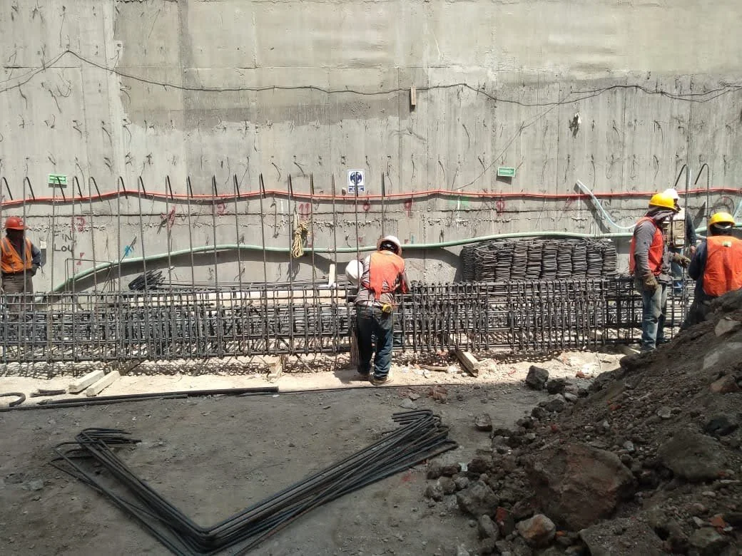Construction workers in safety gear working on a rebar framework at a construction site.