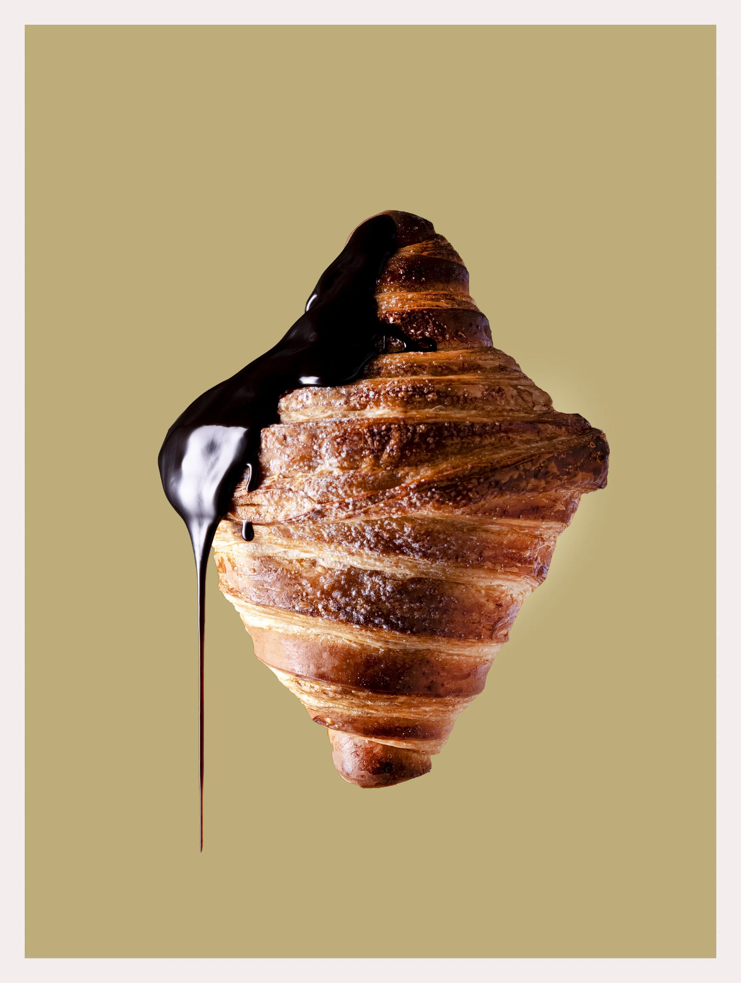 Cono di pasta sfoglia con cioccolato liquido che cola dal centro in uno sfondo beige
