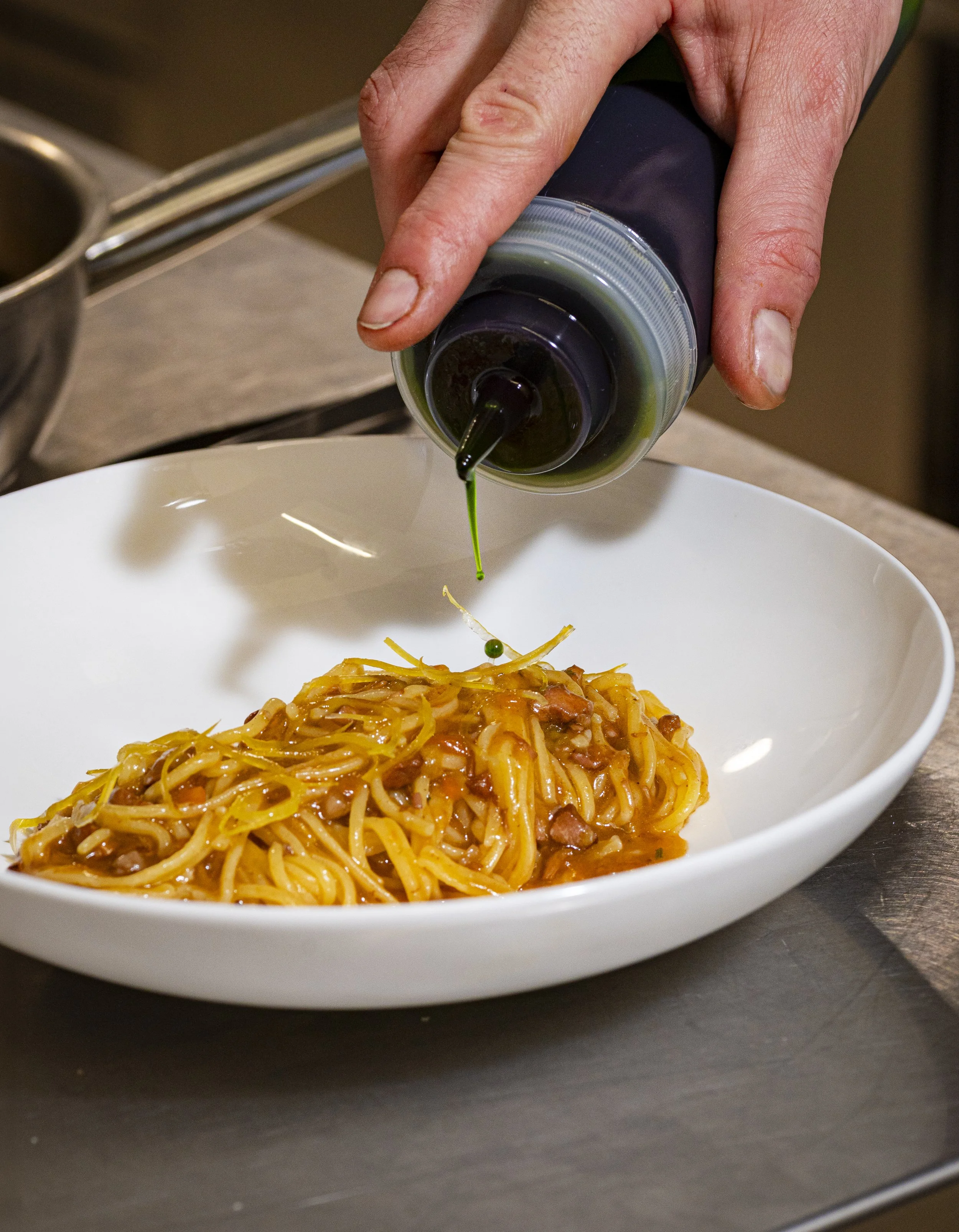 Una forchetta versa salsa su un piatto di spaghetti con carne.