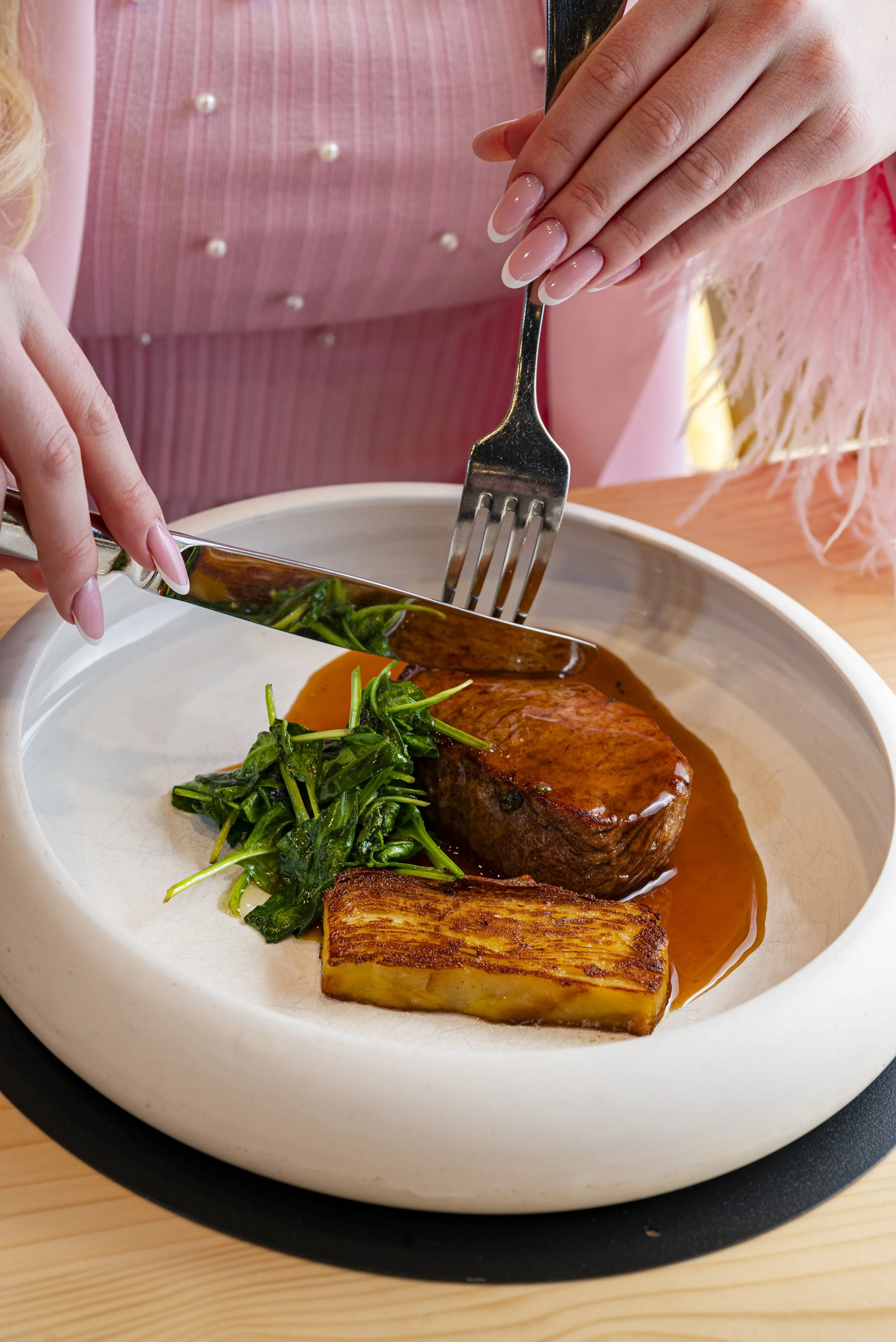 Piatto di carne con contorni di verdure e patate, servito in una ciotola bianca.