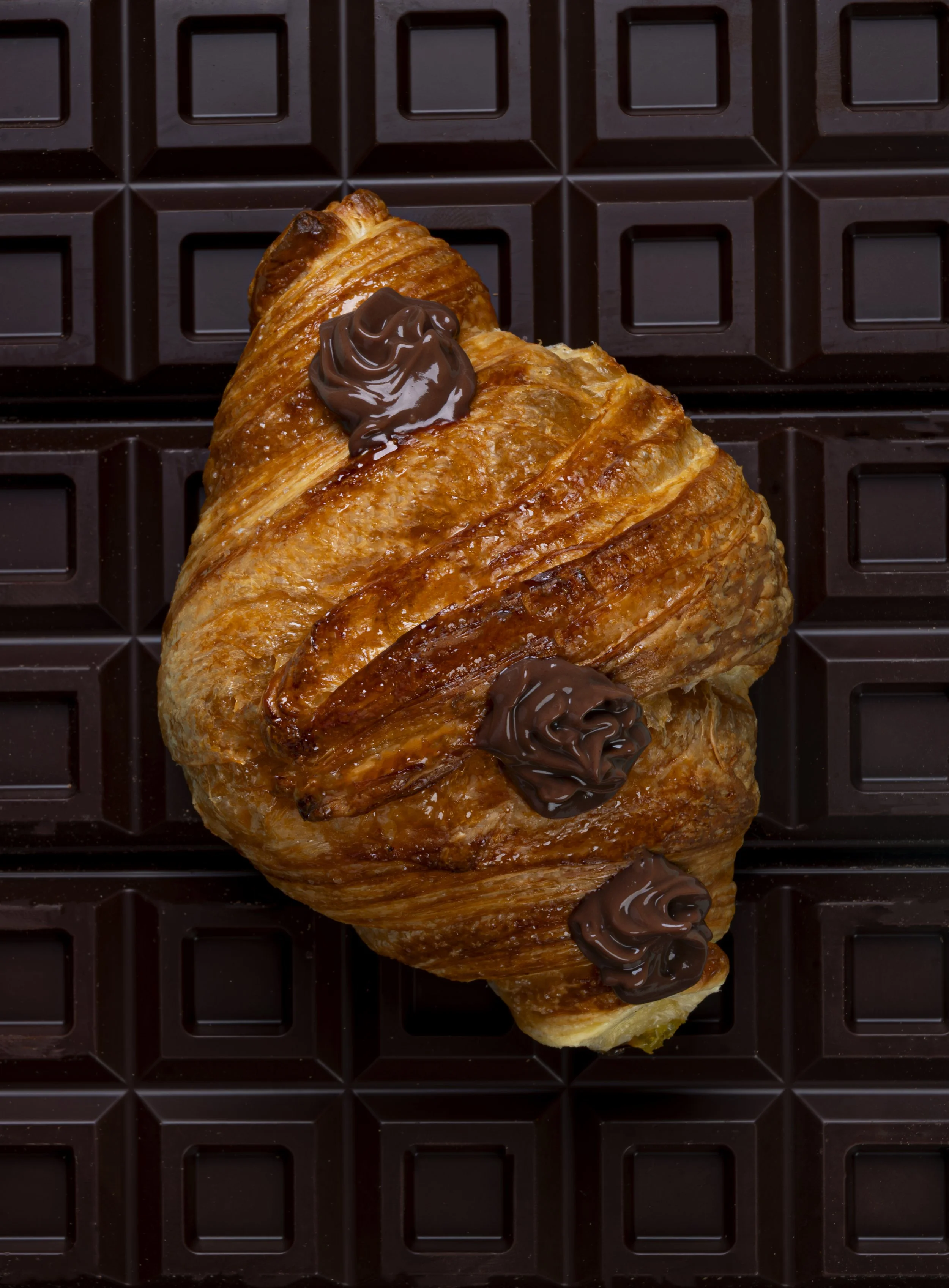 Croissant con cioccolato fondente su una superficie di cioccolato