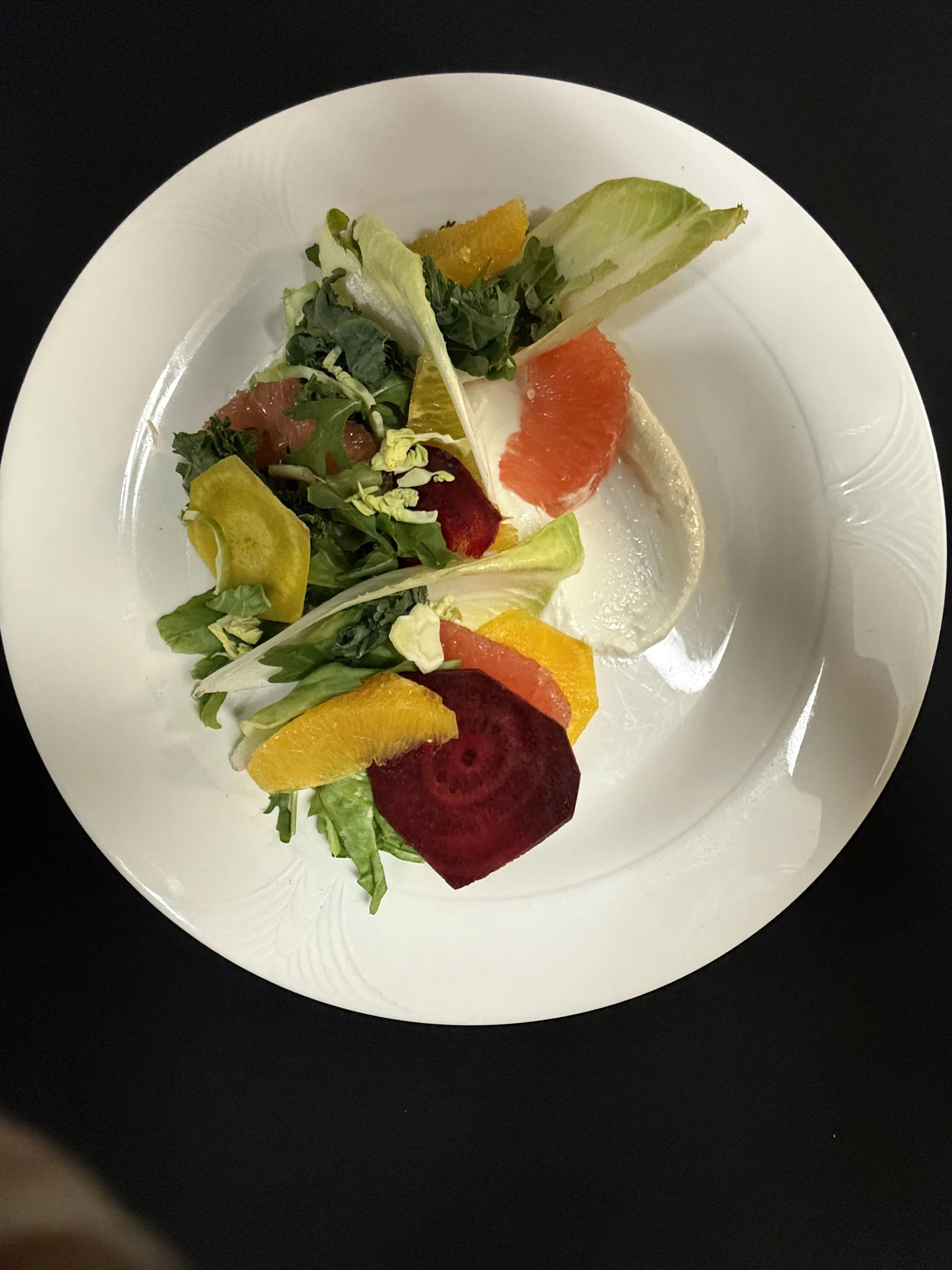 Mixed salad with various vegetables and fruits on a white plate.
