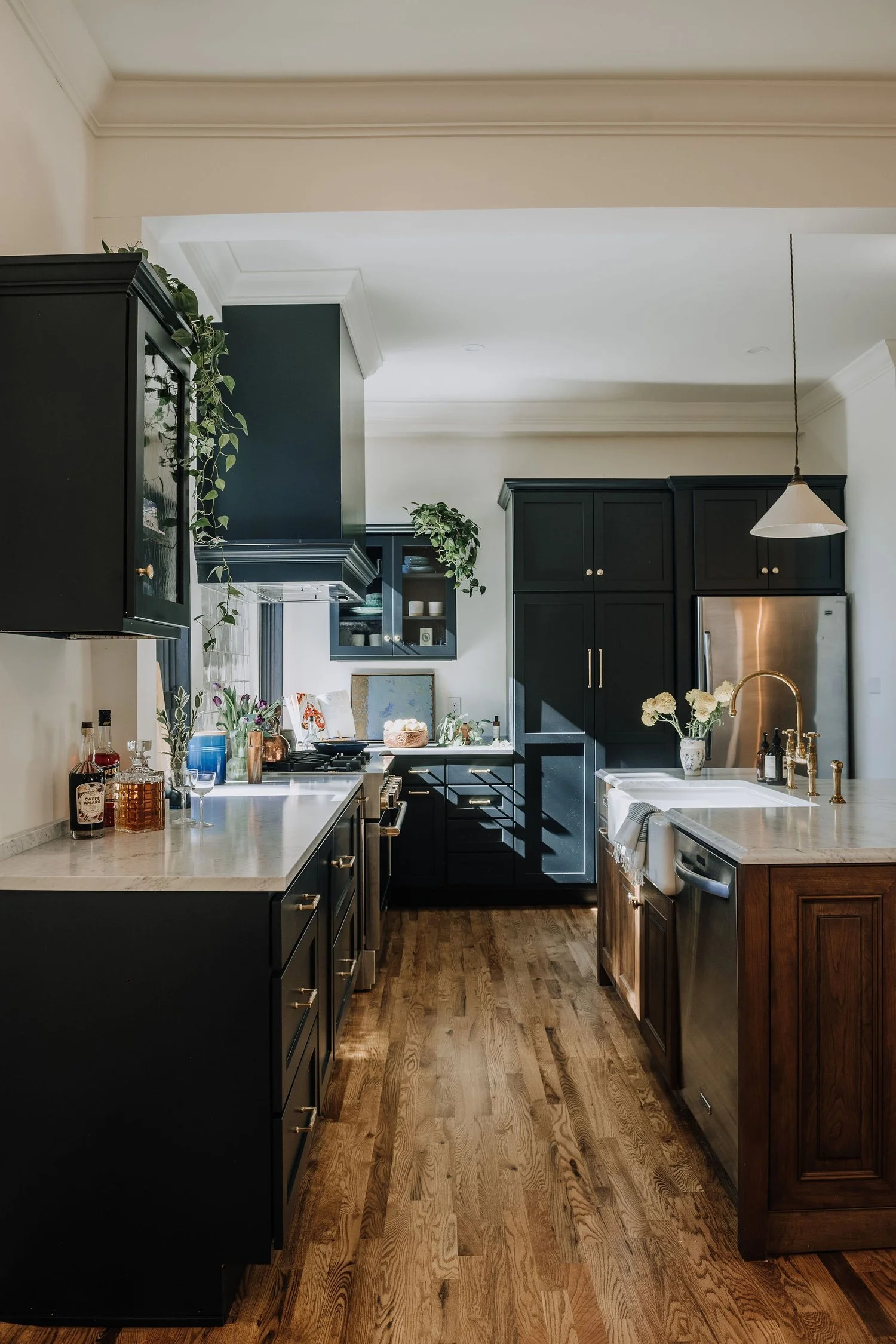Modern kitchen with black cabinets, wooden countertops, and hardwood floors, decorated with plants and flowers. Historic kitchen renovation by Charleston Interior Designer. 