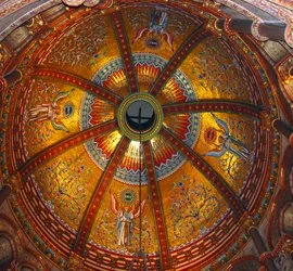 Colorful ornate mosaic ceiling with religious figures and patterns in a circular design.