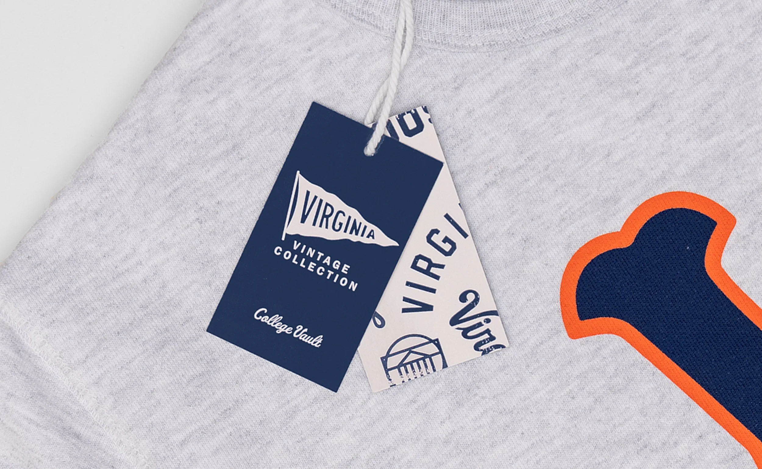 Close-up of a gray hoodie with Virginia college logo embroidery and two tags attached, indicating it is from Virginia's vintage college collection.